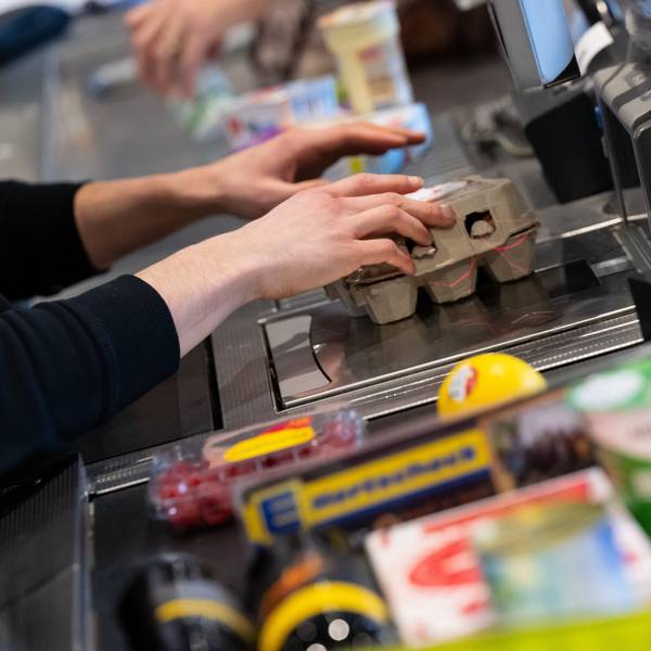 Ein Kassierer scannt in einem Supermarkt an der Kasse die Produkte ein.