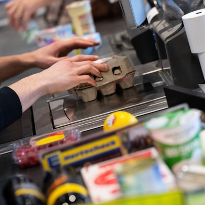 Ein Kassierer scannt in einem Supermarkt an der Kasse die Produkte ein.