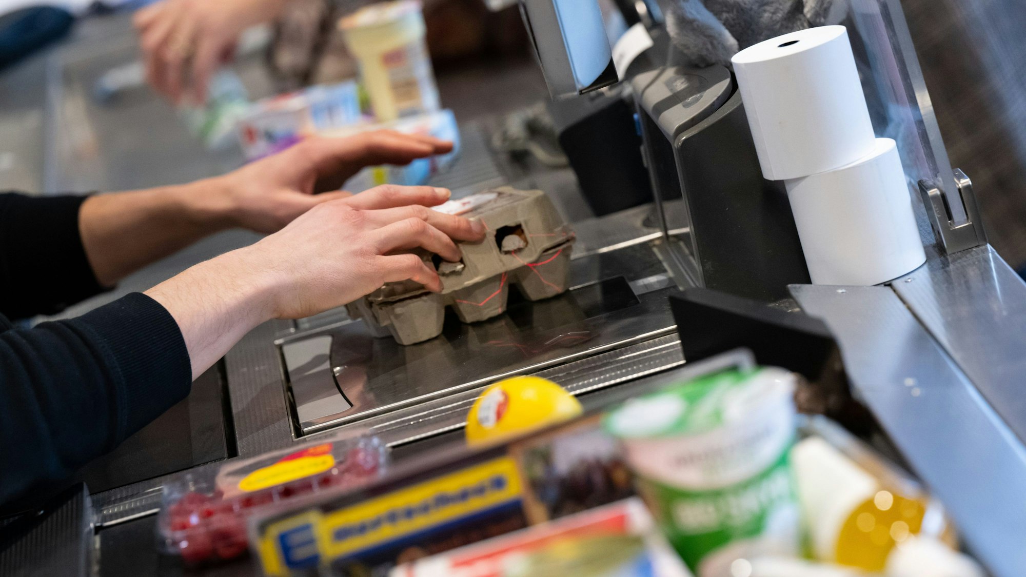 Ein Kassierer scannt in einem Supermarkt an der Kasse die Produkte ein.