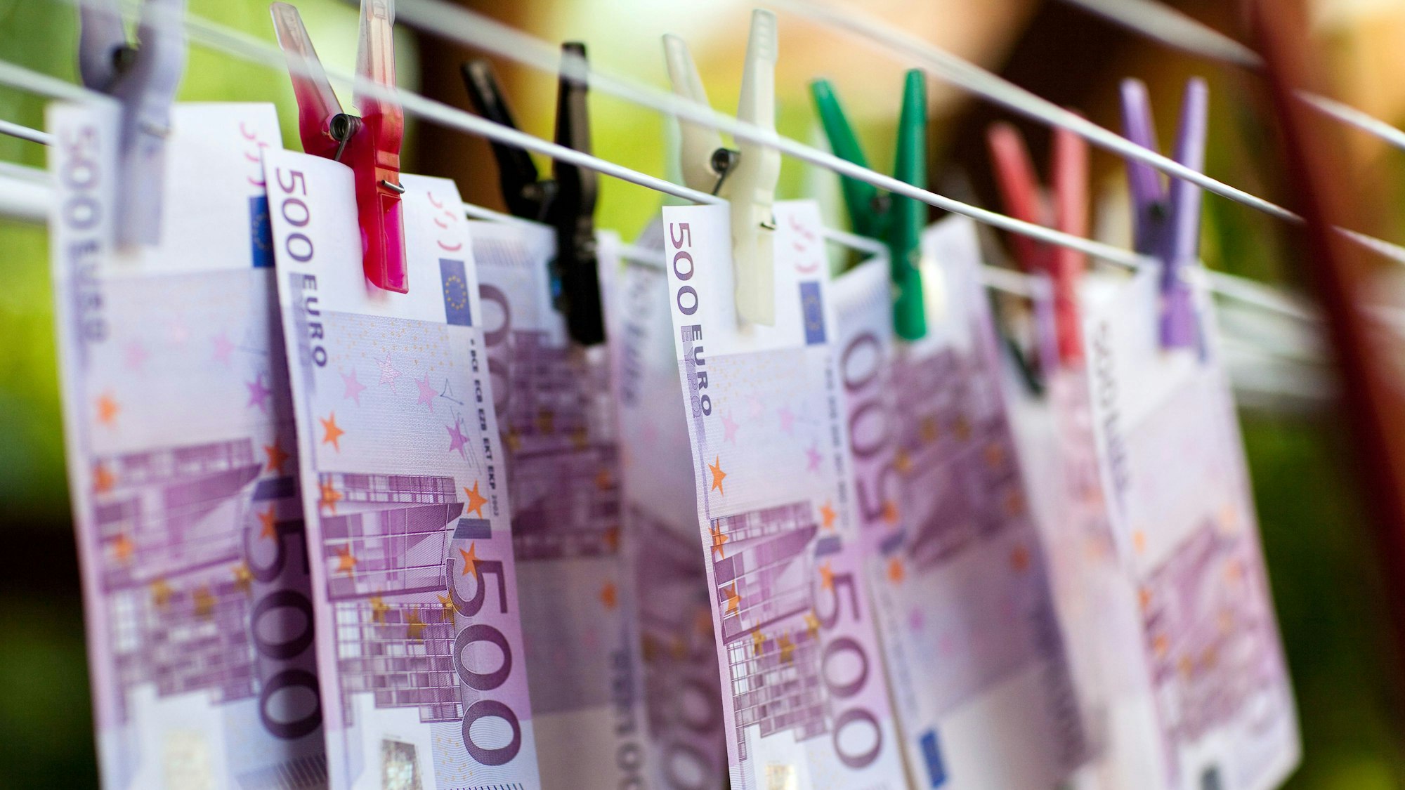 An einem Wäscheständer hängen, mit Klammern befestigt, mehrere 500-Euro-Scheine (Symbolbild).