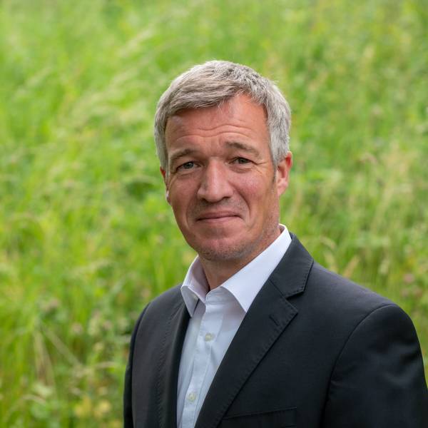 Ein Mann im Anzug lächelt in die Kamera.