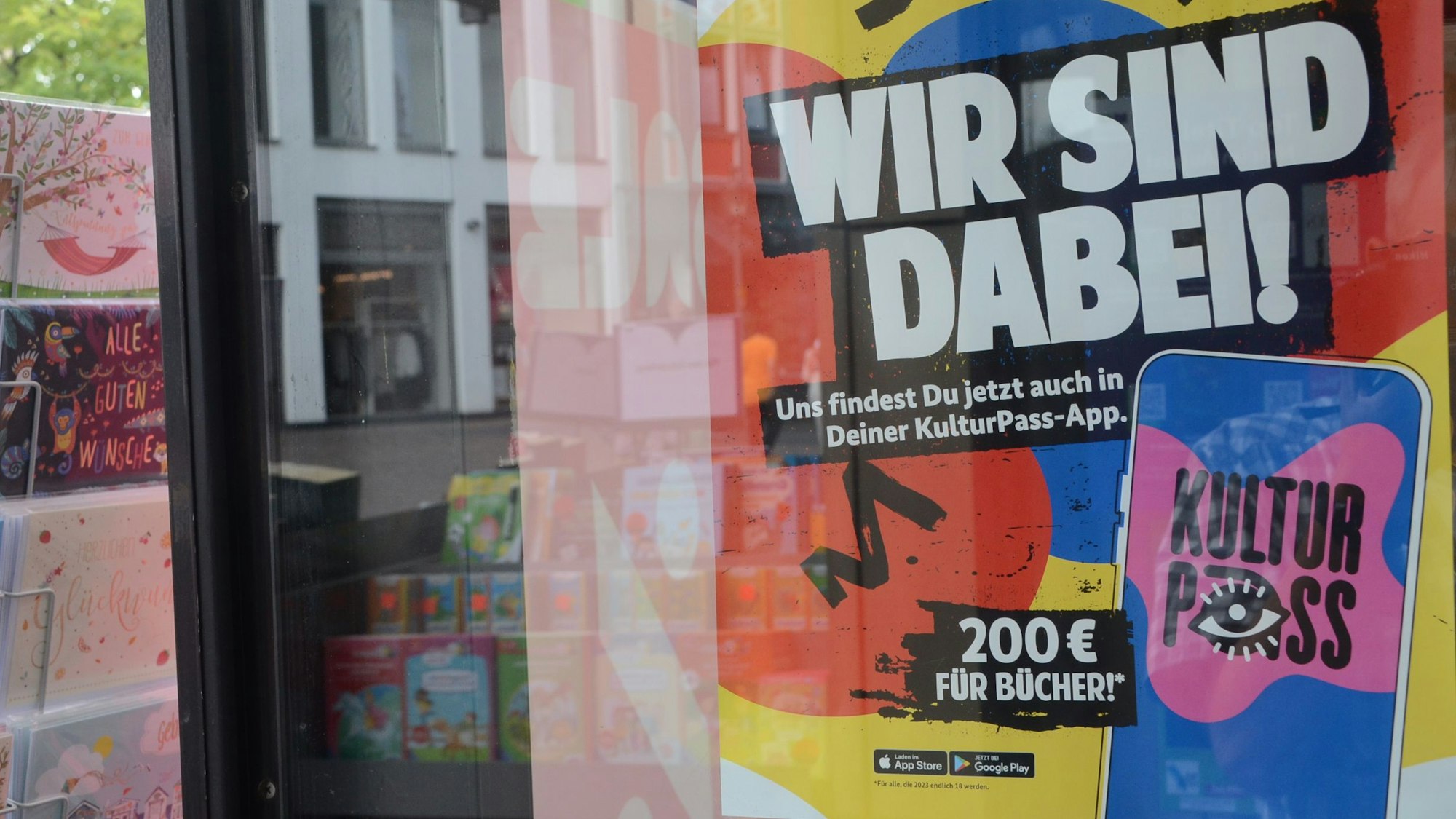 Auf einem bunten Plakat im Schaufenster einer Buchhandlung steht „Wir sind dabei“.