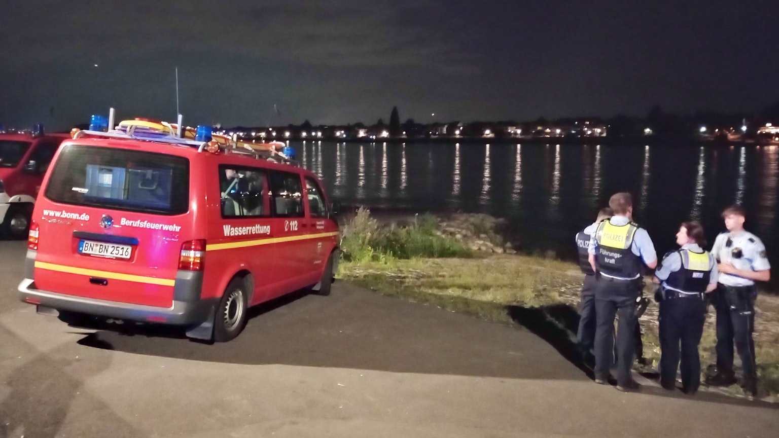 Rettungskräfte blicken auf das Wasser.