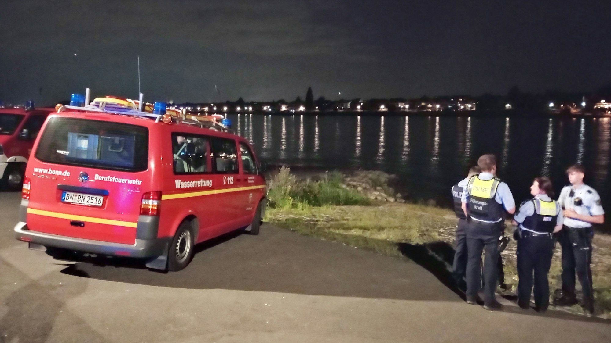 Rettungskräfte blicken auf das Wasser.
