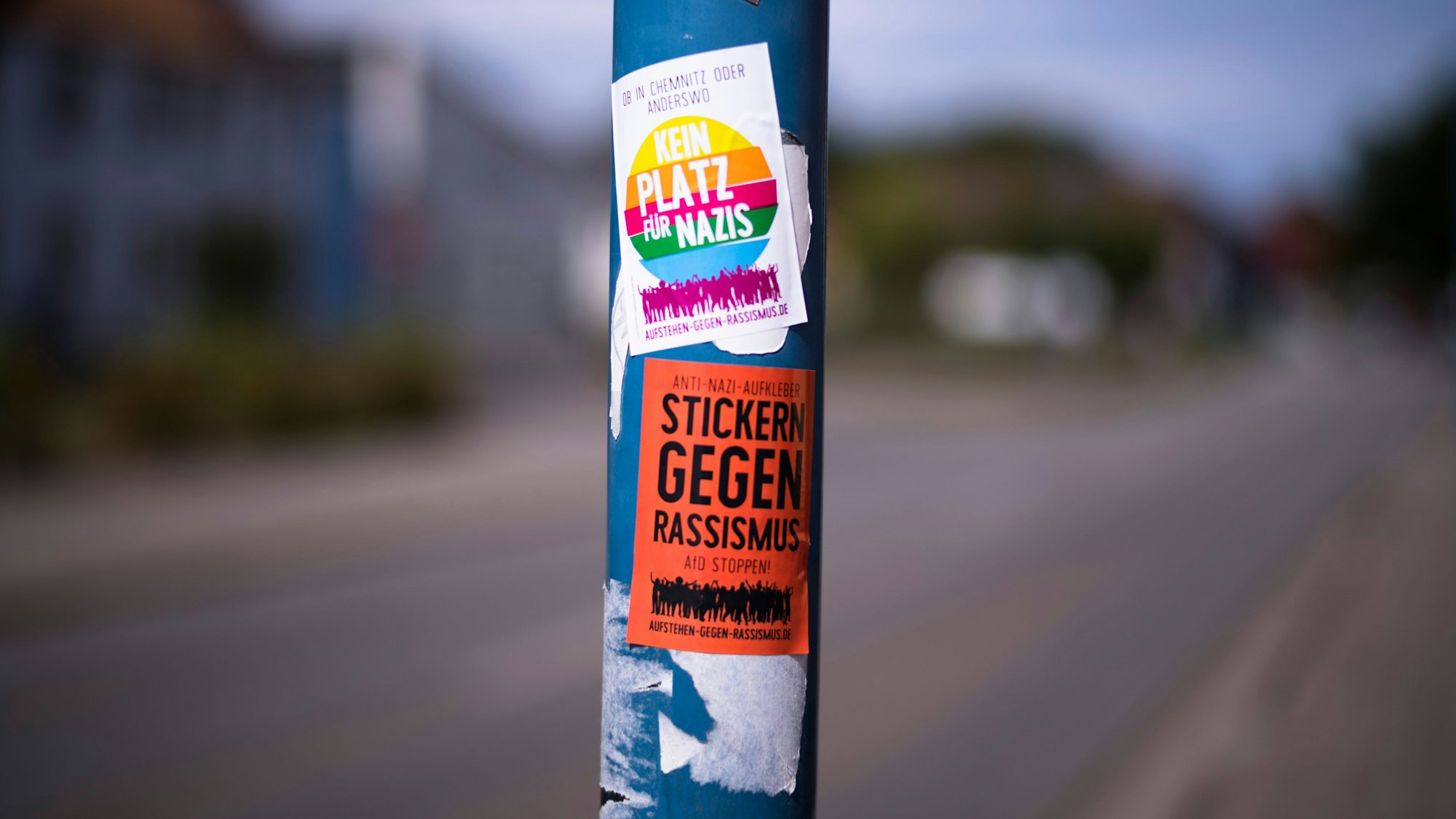 Auf einer Straßenlaterne sind Sticker gegen Nazis und Rassismus aufgeklebt.