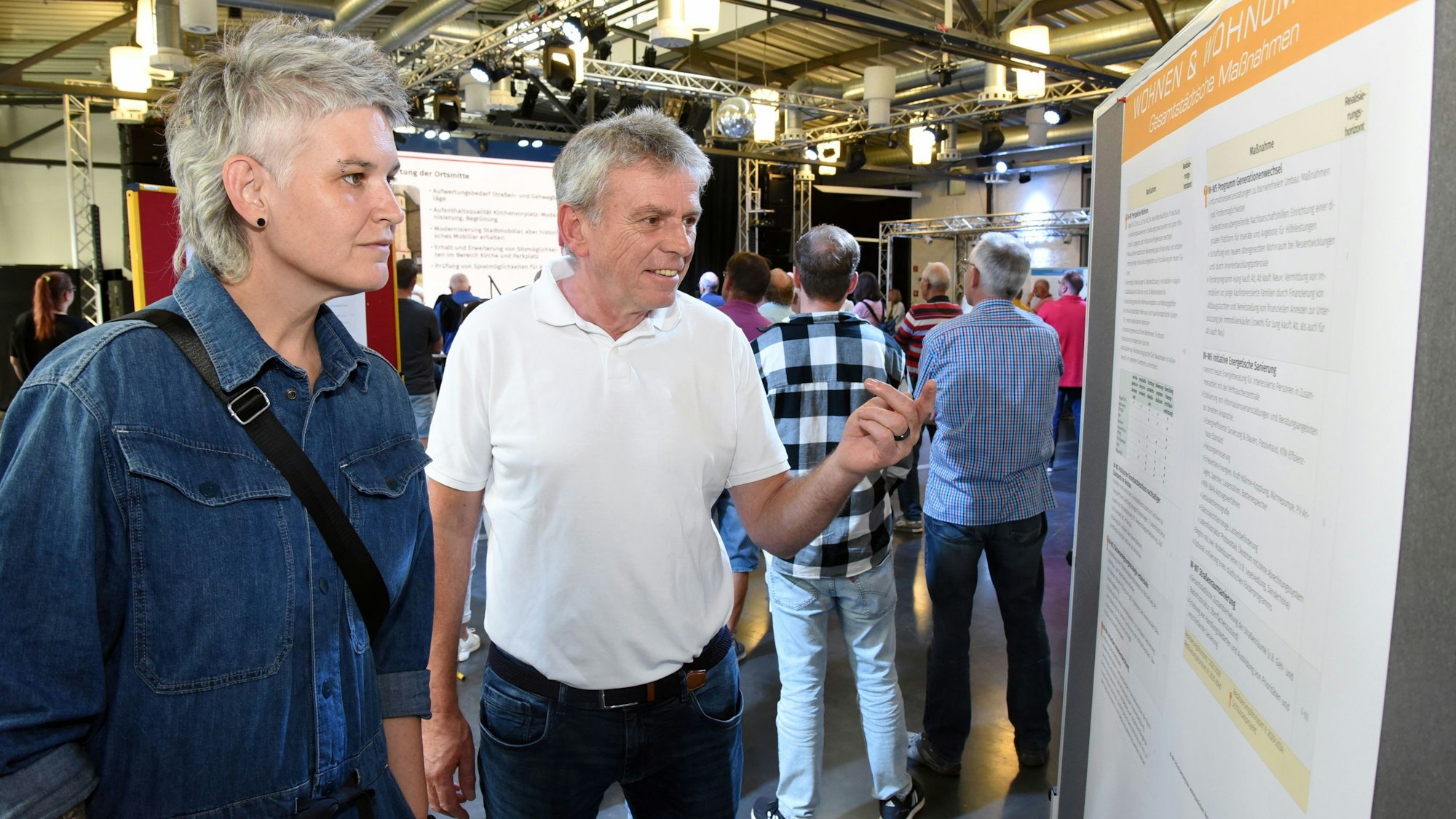 Zwei Personen stehen vor einem Schaubild und informieren sich über das  Integrierte Stadtentwicklungskonzept.