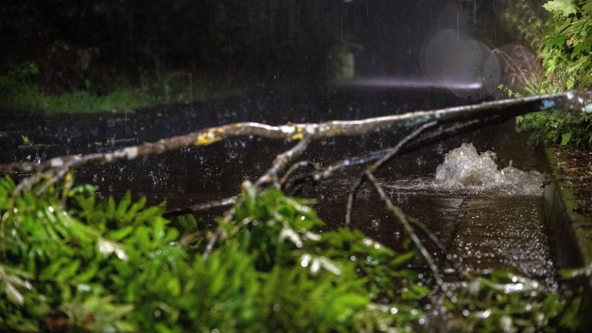 Thüringen, Heldburg: Ein abgebrochener Ast liegt auf einer Straße, aus einem Abflussschlacht sprudelt das Wasser. Weite Teile von Deutschland wurden von Unwettern heimgesucht.