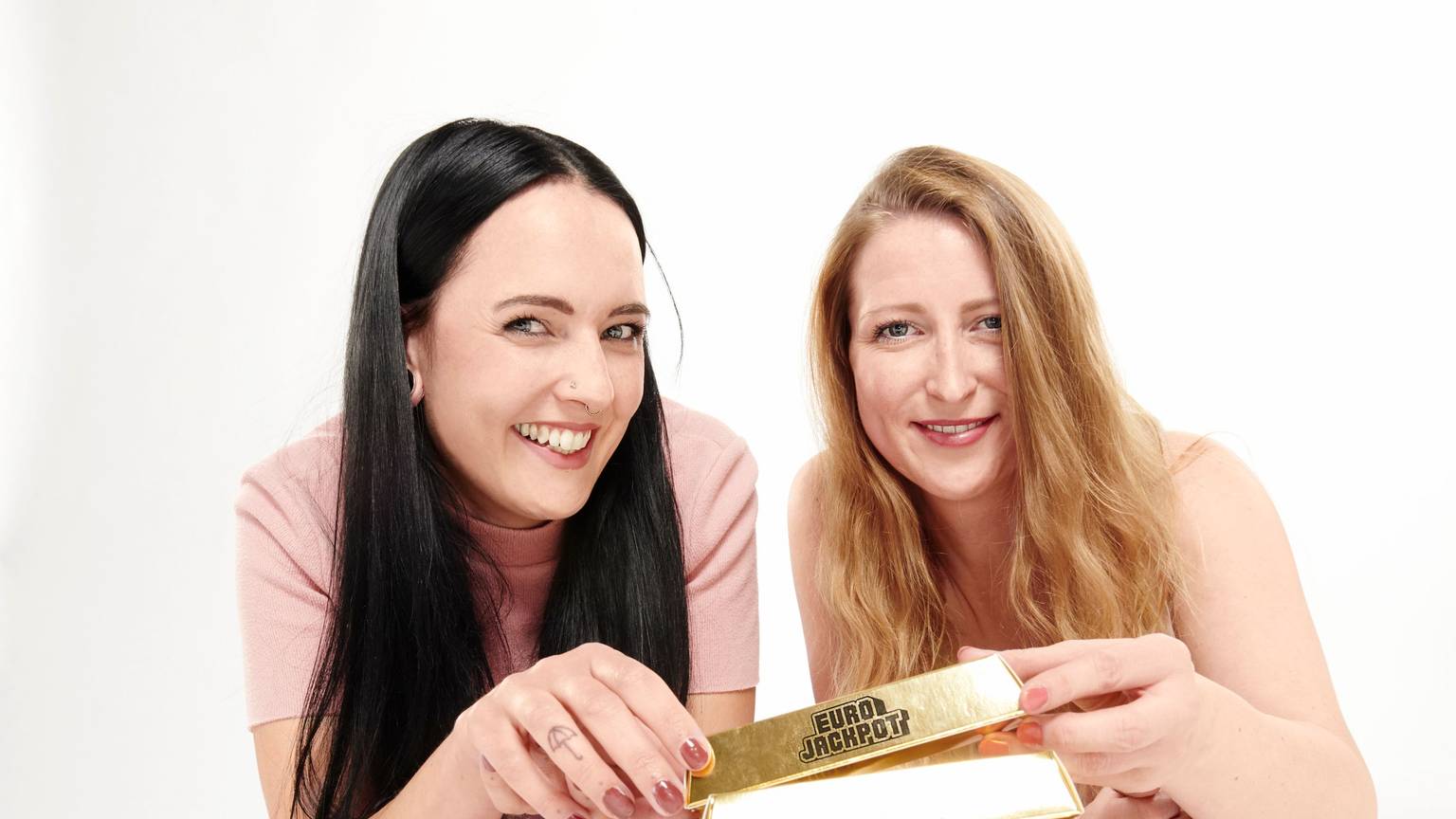 Zwei Frauen mit Eurojackpot Goldbarren in der Hand.