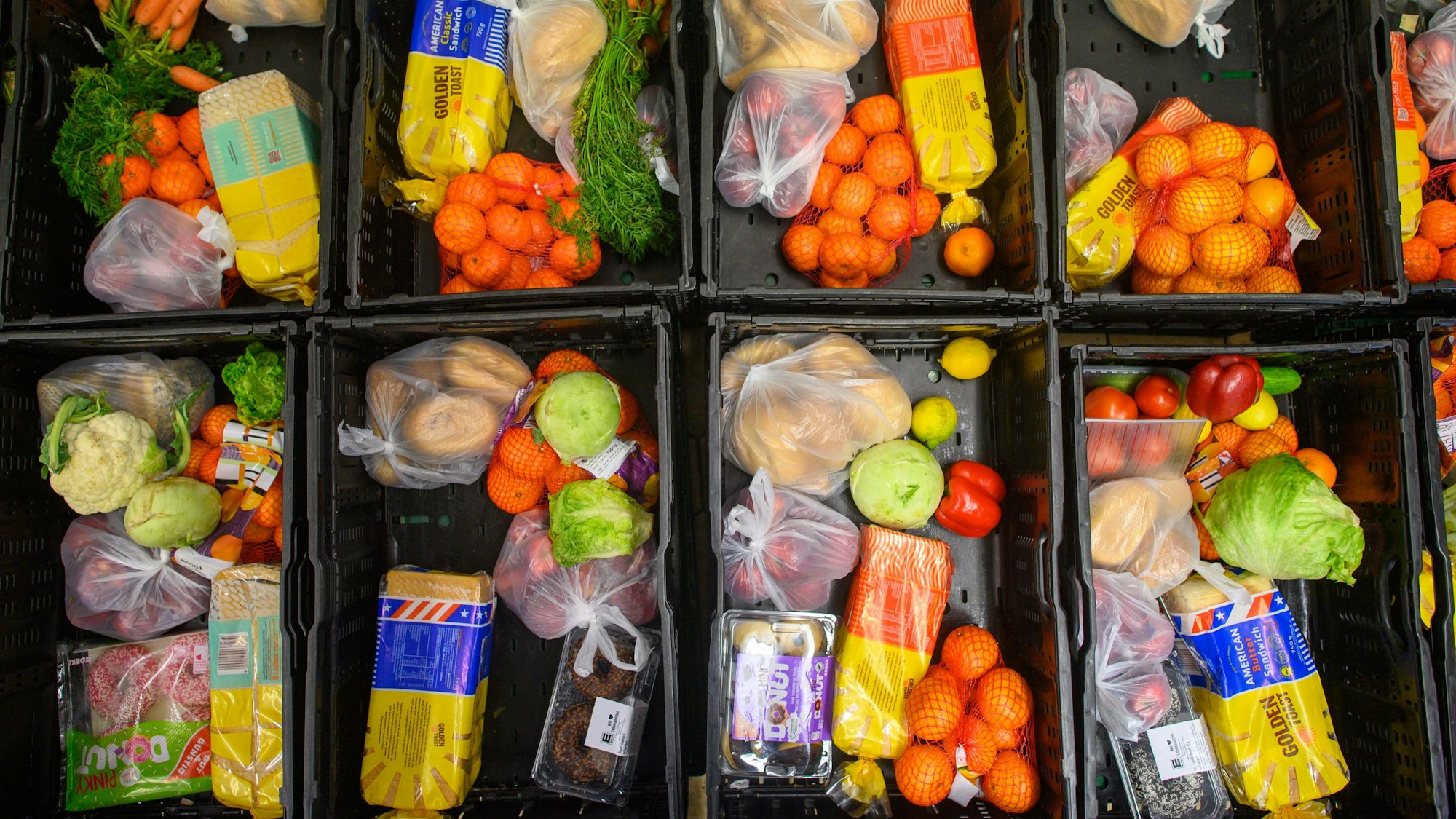 Abgepackt in große Plastikkörbe warten verschiedene Lebensmittel wie Obst, Gemüse und Brot auf die Verteilung an Bedürftige.