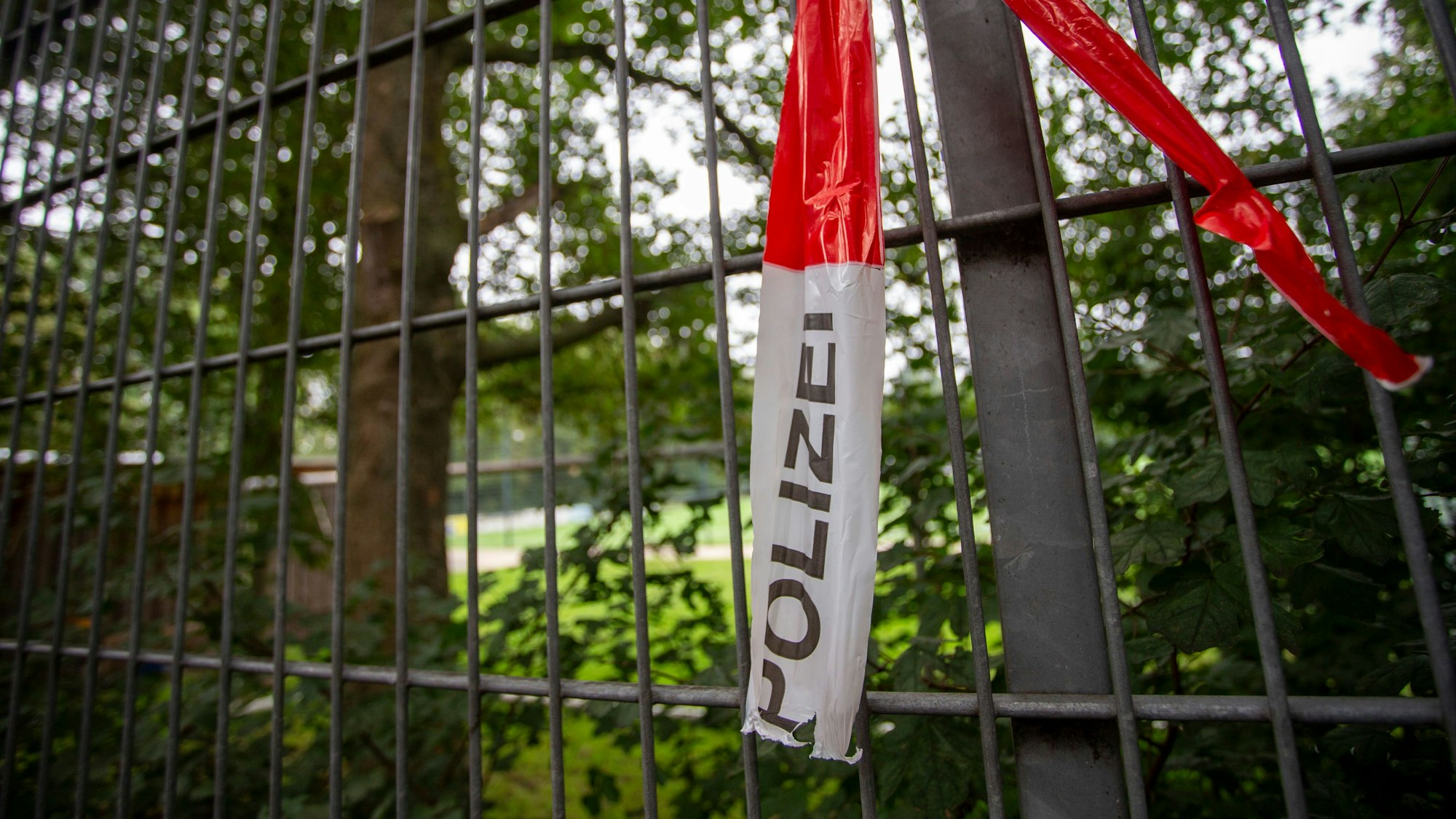 Reste eines Absperrbands der Polizei hängen am Zaun des Fußbalplatzes in der Wuppertaler Straße in Buchheim.