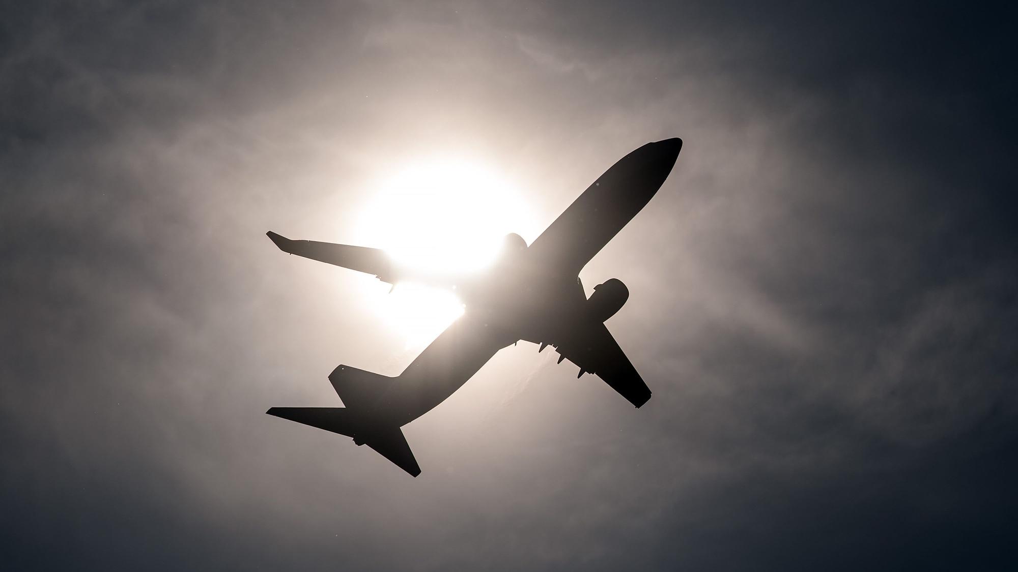 Ein Flugzeug startet vom Flughafen in Düsseldorf und fliegt an der Sonne vorbei.
