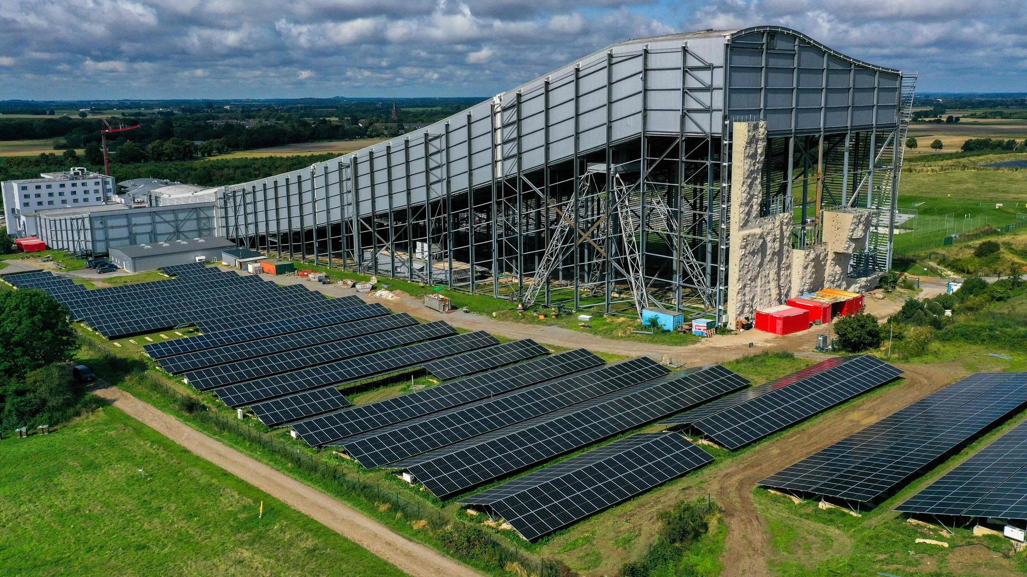 Eine Luftaufnahme zeigt eine große Freiflächen-Photovoltaikanlage neben der Skihalle in Neuss.