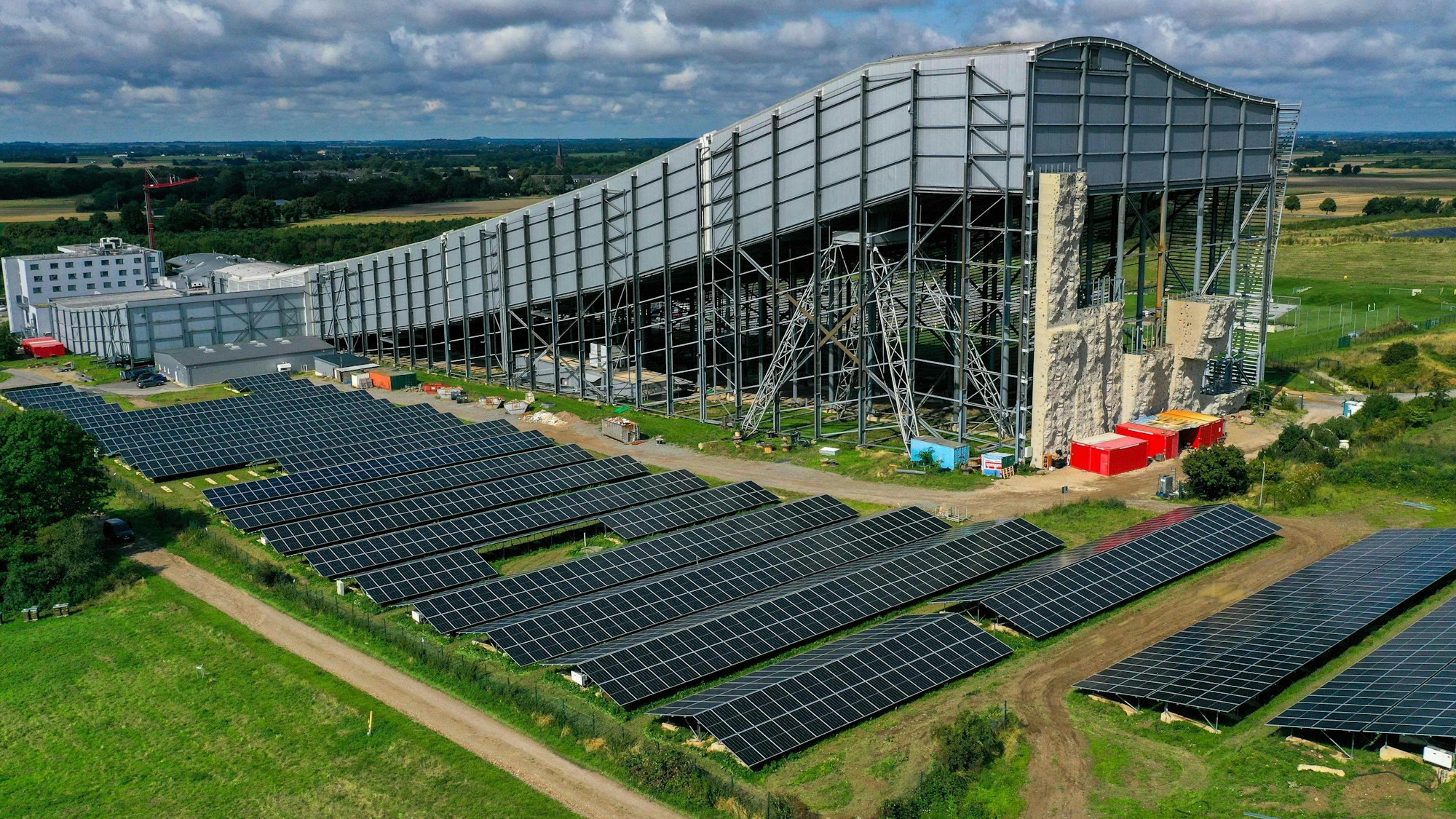 Eine Luftaufnahme zeigt eine große Freiflächen-Photovoltaikanlage neben der Skihalle in Neuss.