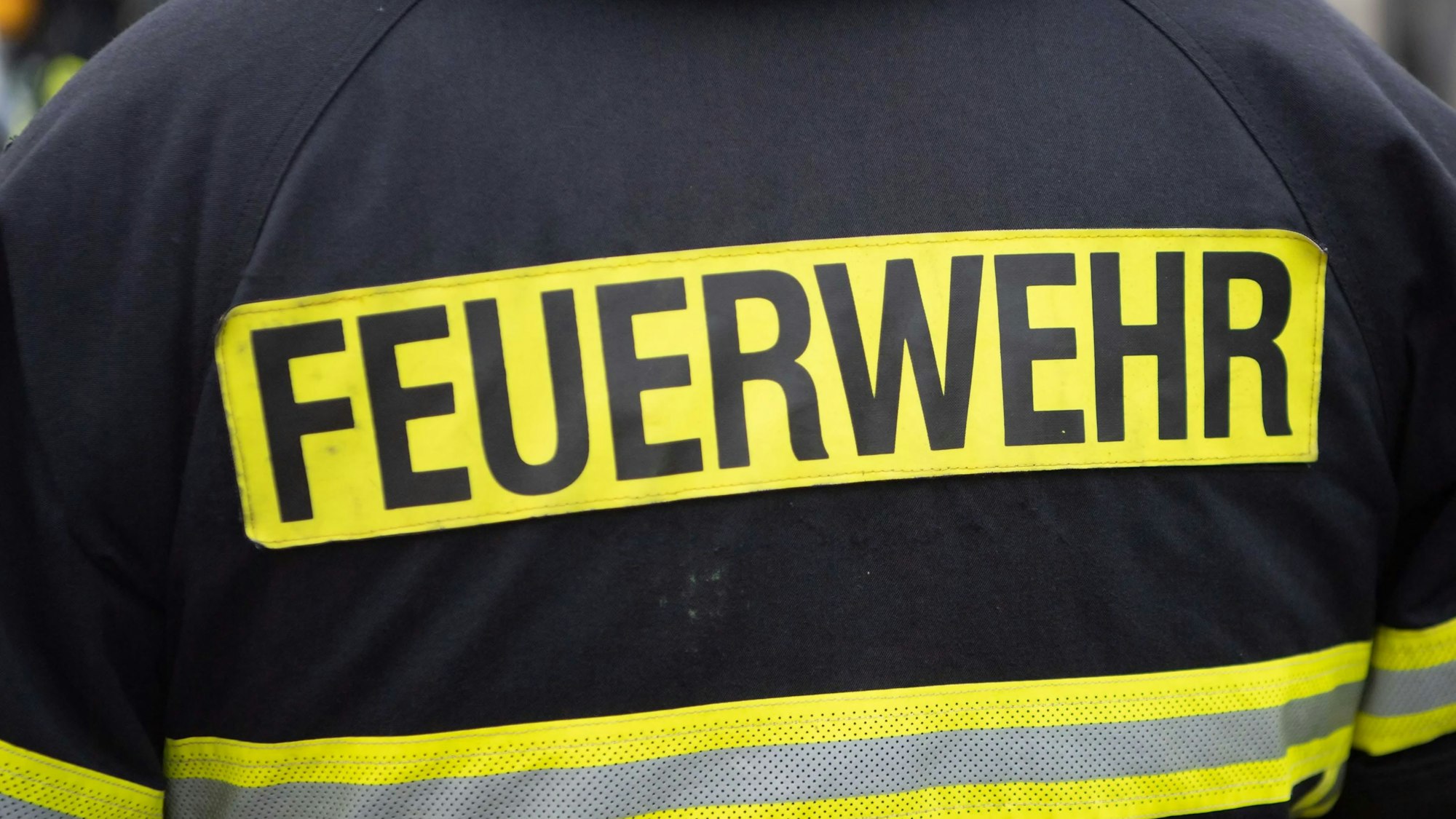 Das Bild zeigt die Einsatzjacke eines Feuerwehrmanns. Auf dem Rücken steht Feuerwehr.
