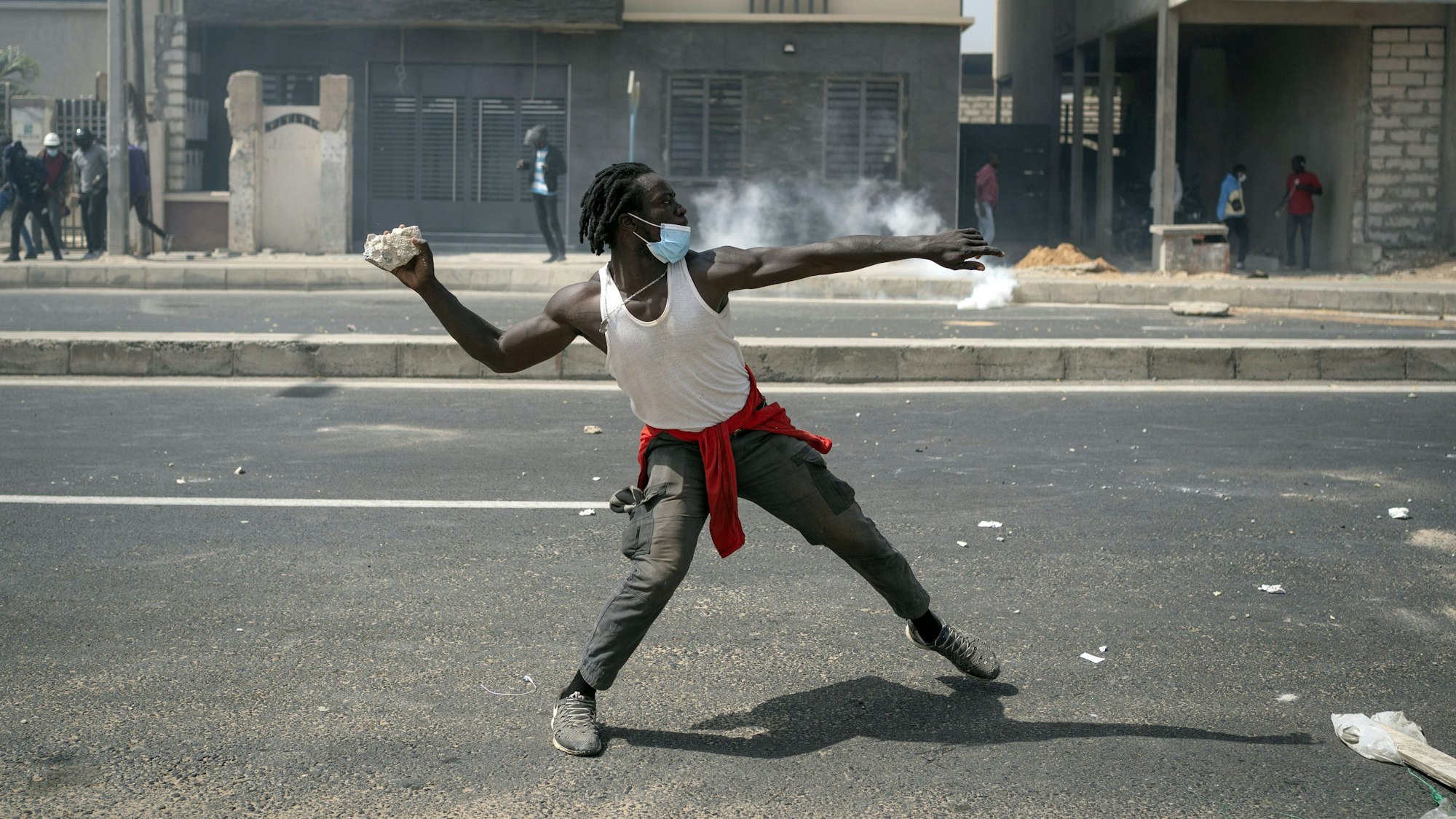 Ein Demonstrierender wirft einen Stein auf die Polizei, während den Aufständen für Ousmane Sonko im Senegal.