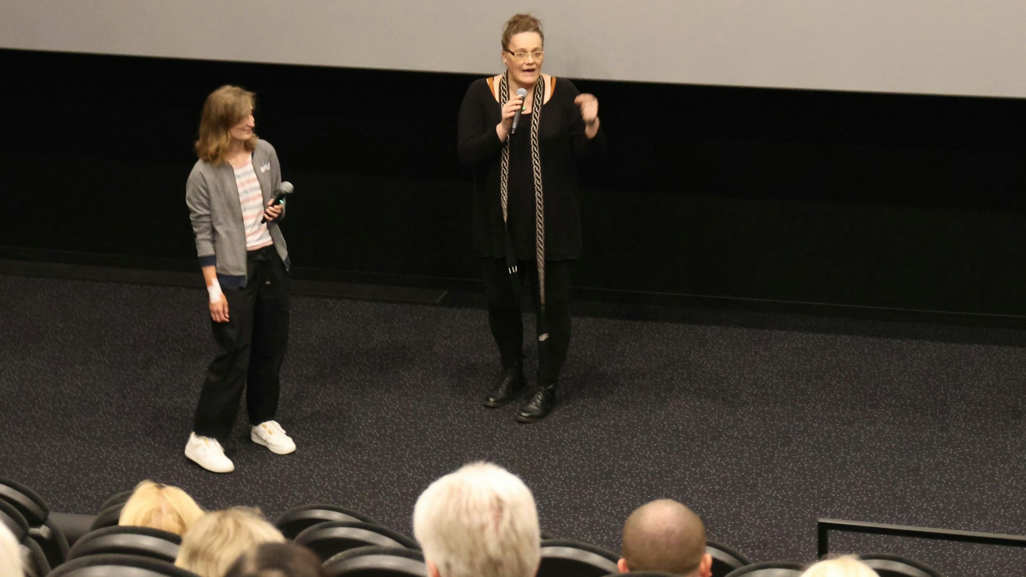 In einem der Säle des Gummersbacher Kinocenters Seven stehen Marie Brück (r.) und Moderatorin Nadine Lindörfer vom Netzwerk gegen Rechts vor der dunklen Leinwand und sprechen über Brücks langen und schmerzhaften Weg vom Mann zur Frau.