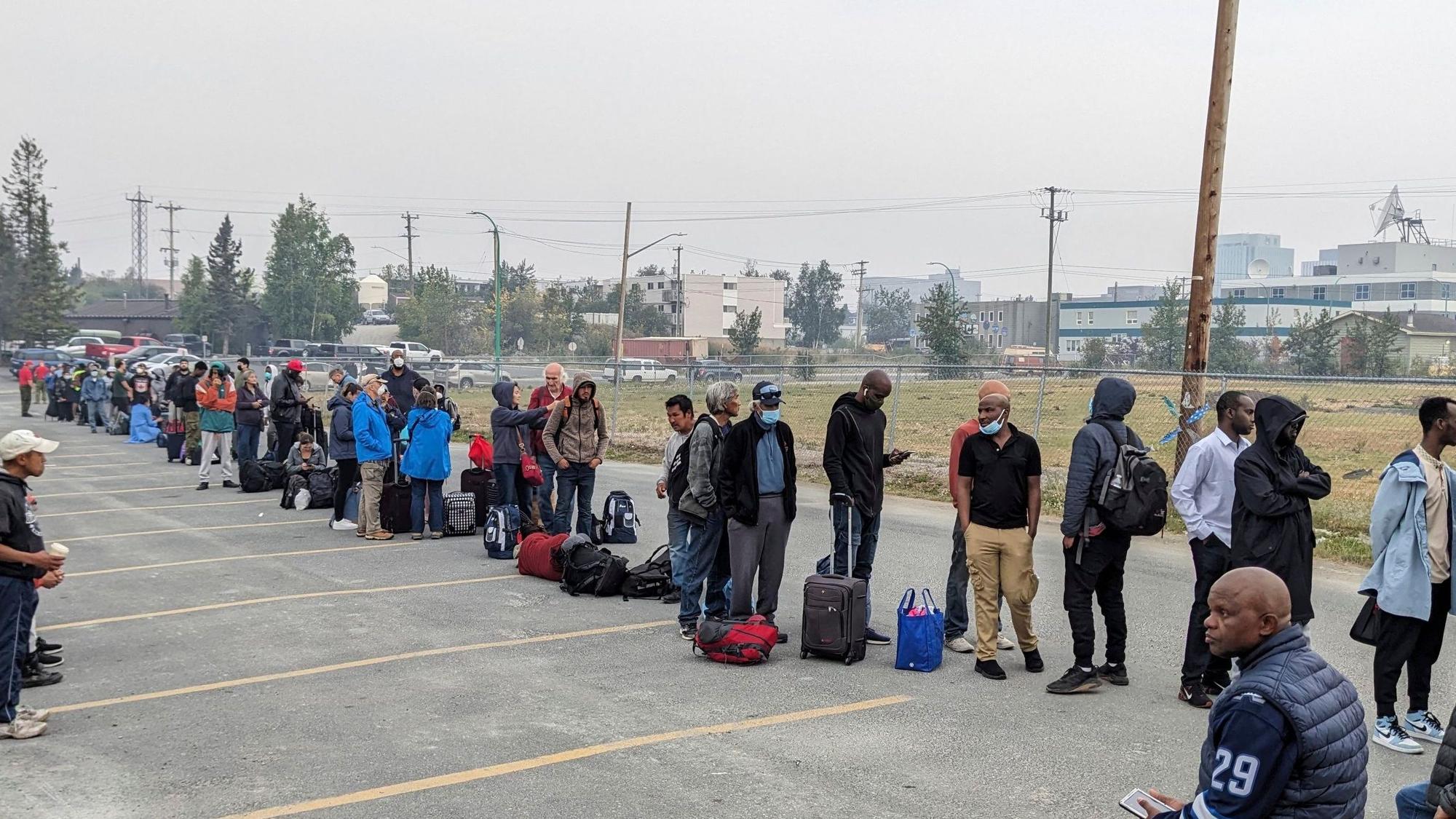 Menschen ohne Fahrzeug stellen sich am Donnerstag in Yellowknife an, um sich für einen Flug nach Calgary, Alberta, anzumelden.