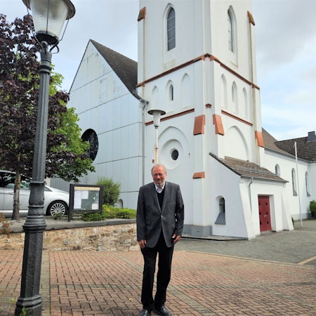 Pfarrer Hans-Joachim Hellwig steht vor der Kaller Pfarrkirche.