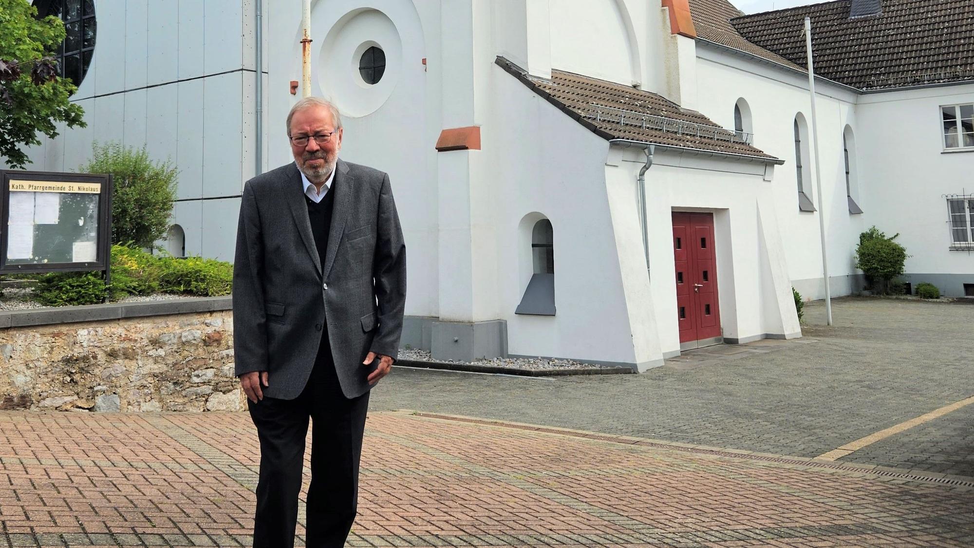 Pfarrer Hans-Joachim Hellwig steht vor der Kaller Pfarrkirche.