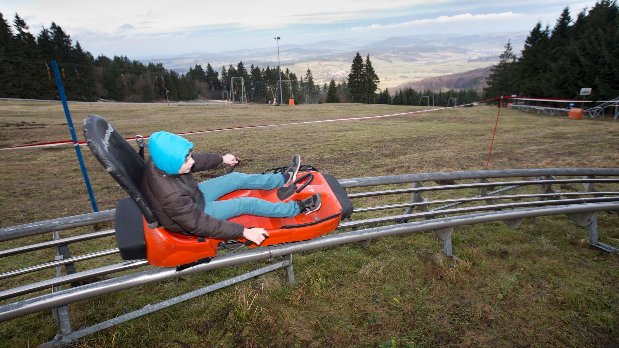 Ein Junge saust auf der Wasserkuppe (Hessen) die Sommerrodelbahn entlang.