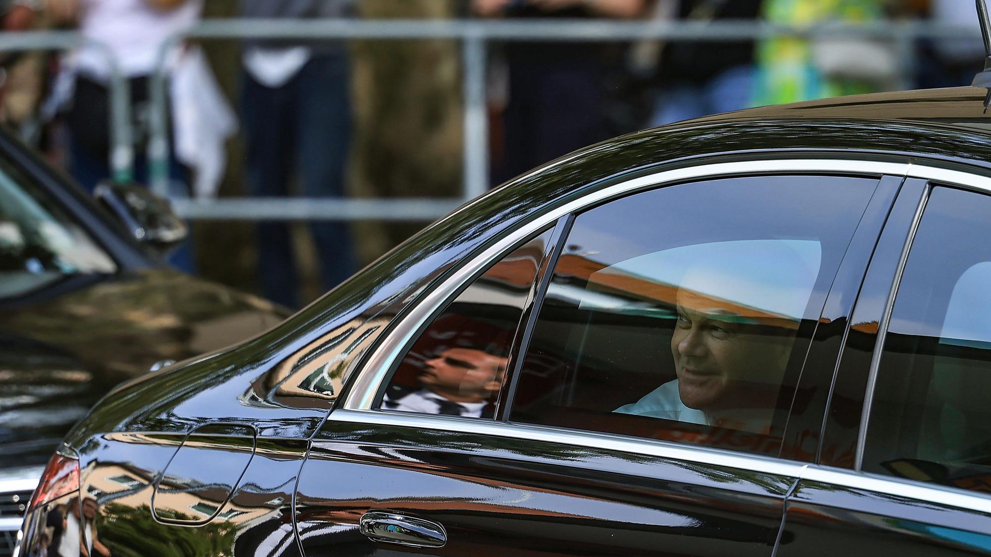 Bundeskanzler Olaf Scholz (SPD) blickt vor einem Büdchen aus seinem Dienstwagen.