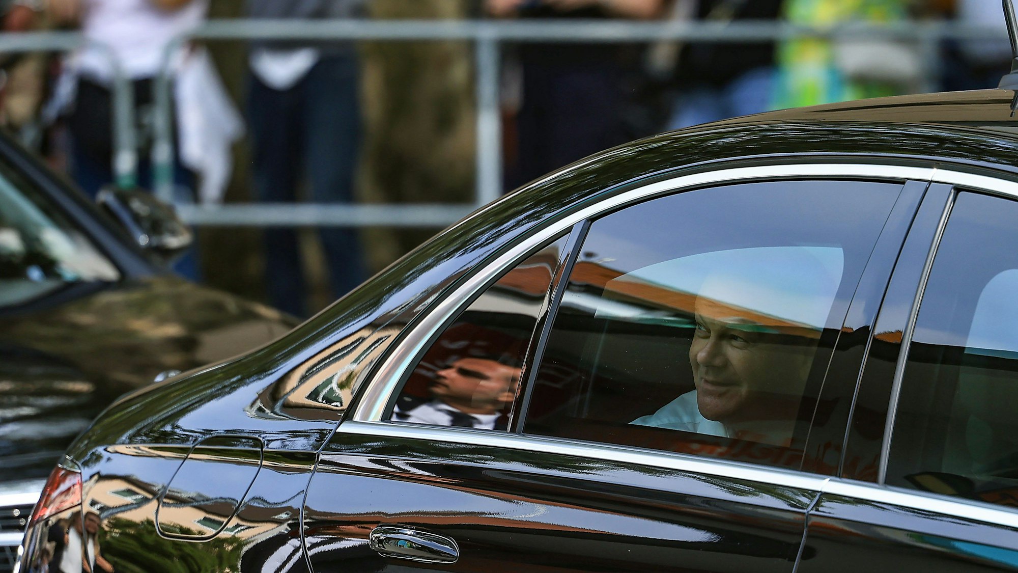 Bundeskanzler Olaf Scholz (SPD) blickt vor einem Büdchen aus seinem Dienstwagen.