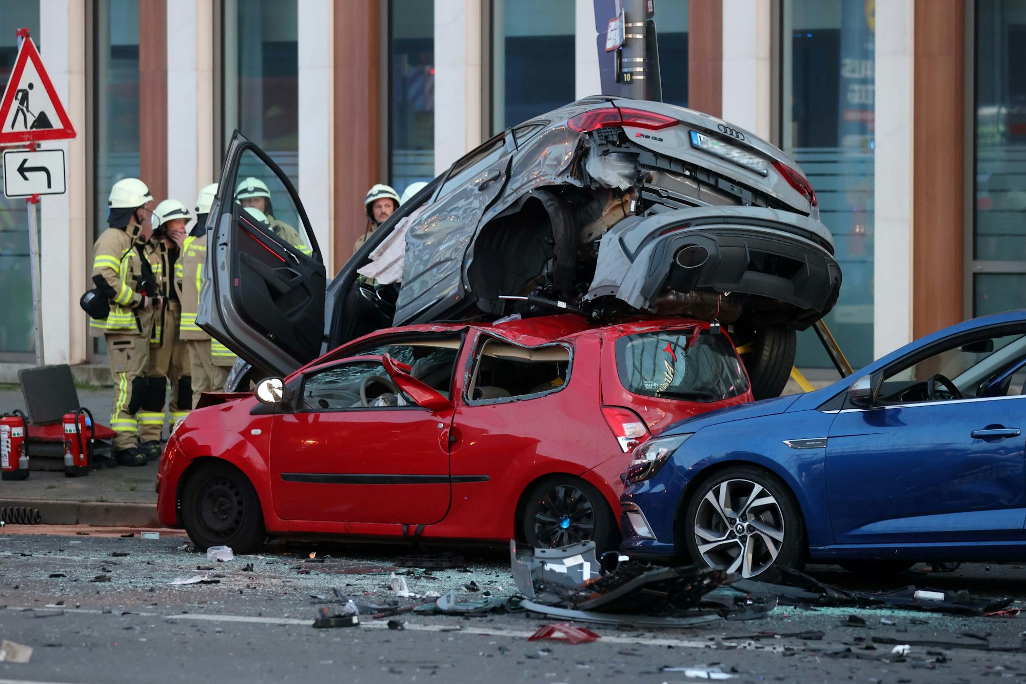Feuerwehrleute neben zertrümmerten Autos.