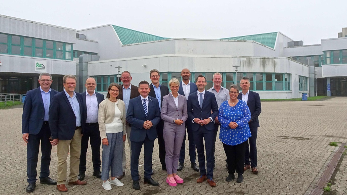 Schulministerin Dorothee Feller (vorne, pinke Schuhe) und Meckenheims Bürgermeister Holger Jung (links daneben) mit Vertretern der Verwaltung und den Leitungen der drei weiterführenden Schulen auf dem Schulcampus vor Gymnasium und Hauptschule.