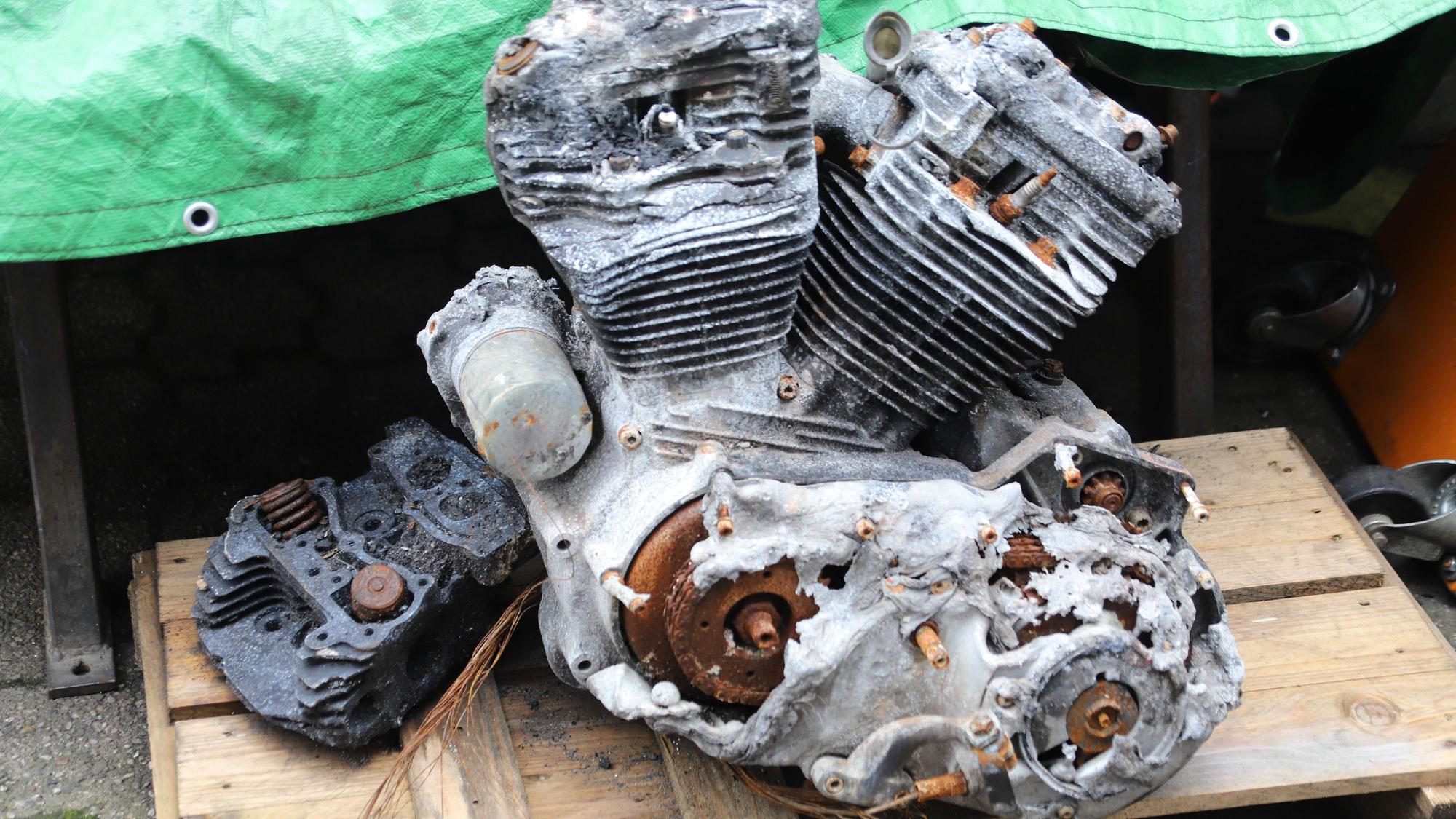 Ein weitgehend geschmolzener Motor liegt auf einer Palette.