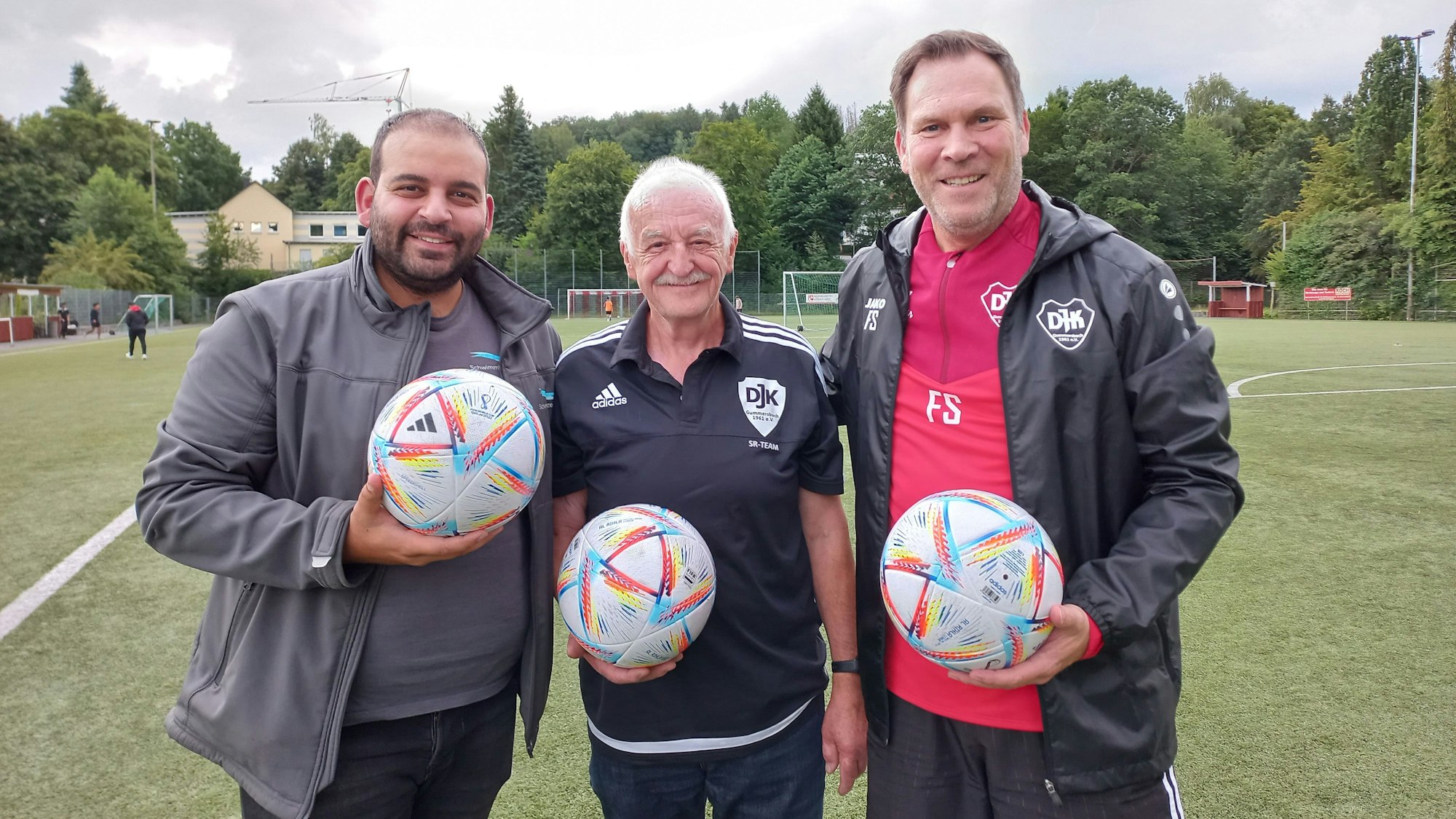 Zu sehen sind drei Männer, die jeweils einen Fußball in der Hand halten.