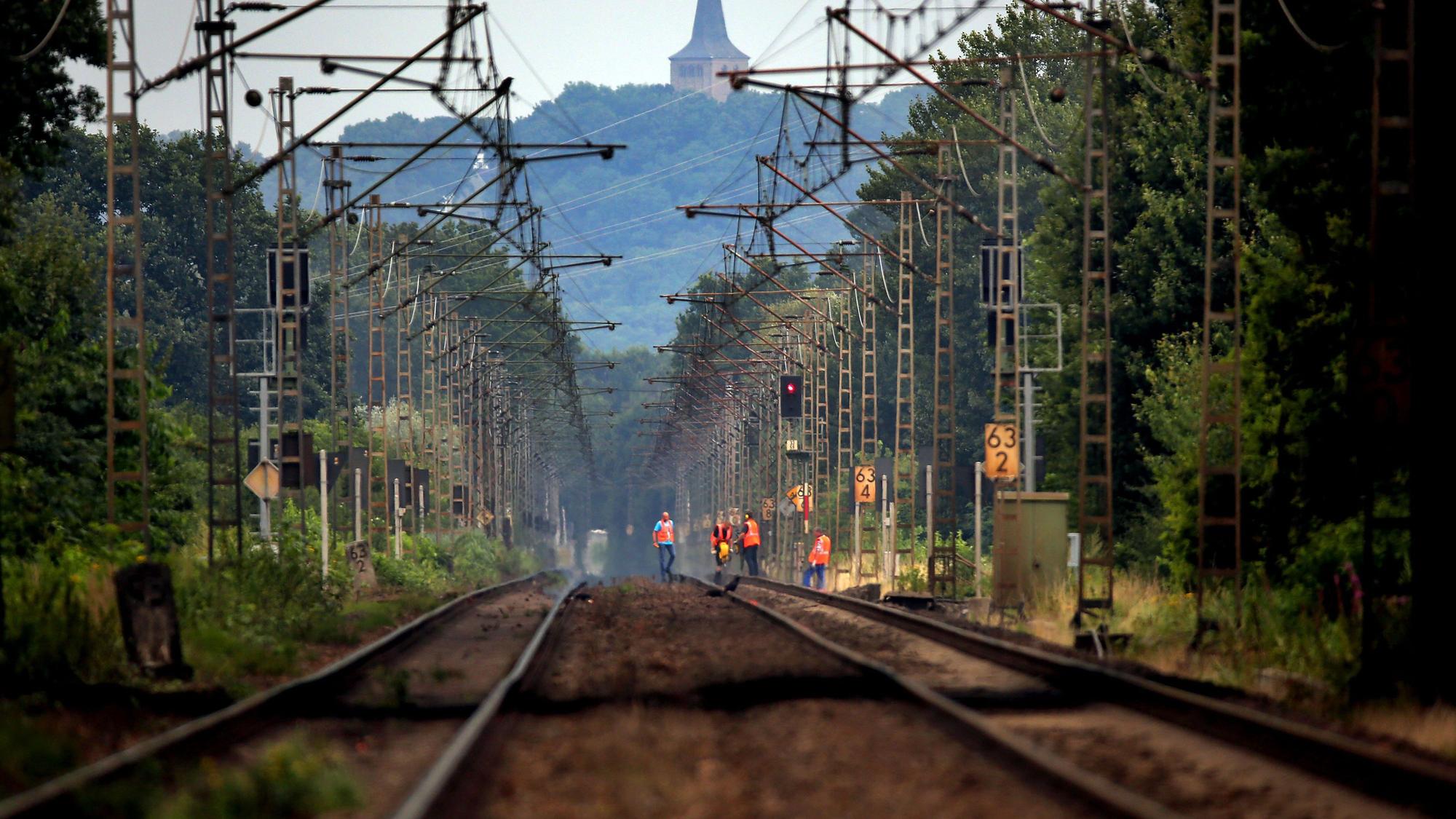 Bahn-Mitarbeiter laufen über die Bahngleise.
