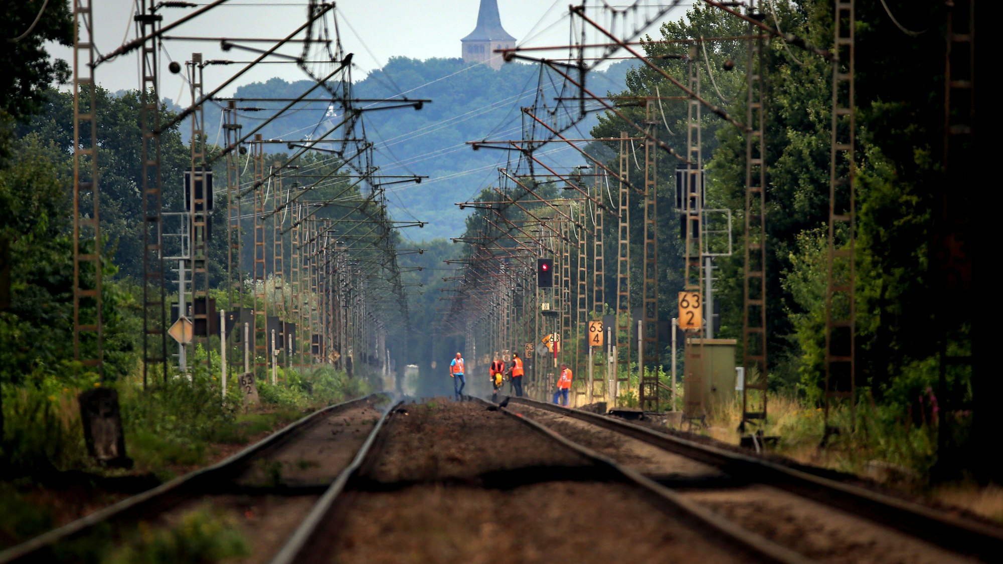 Bahn-Mitarbeiter laufen über die Bahngleise.