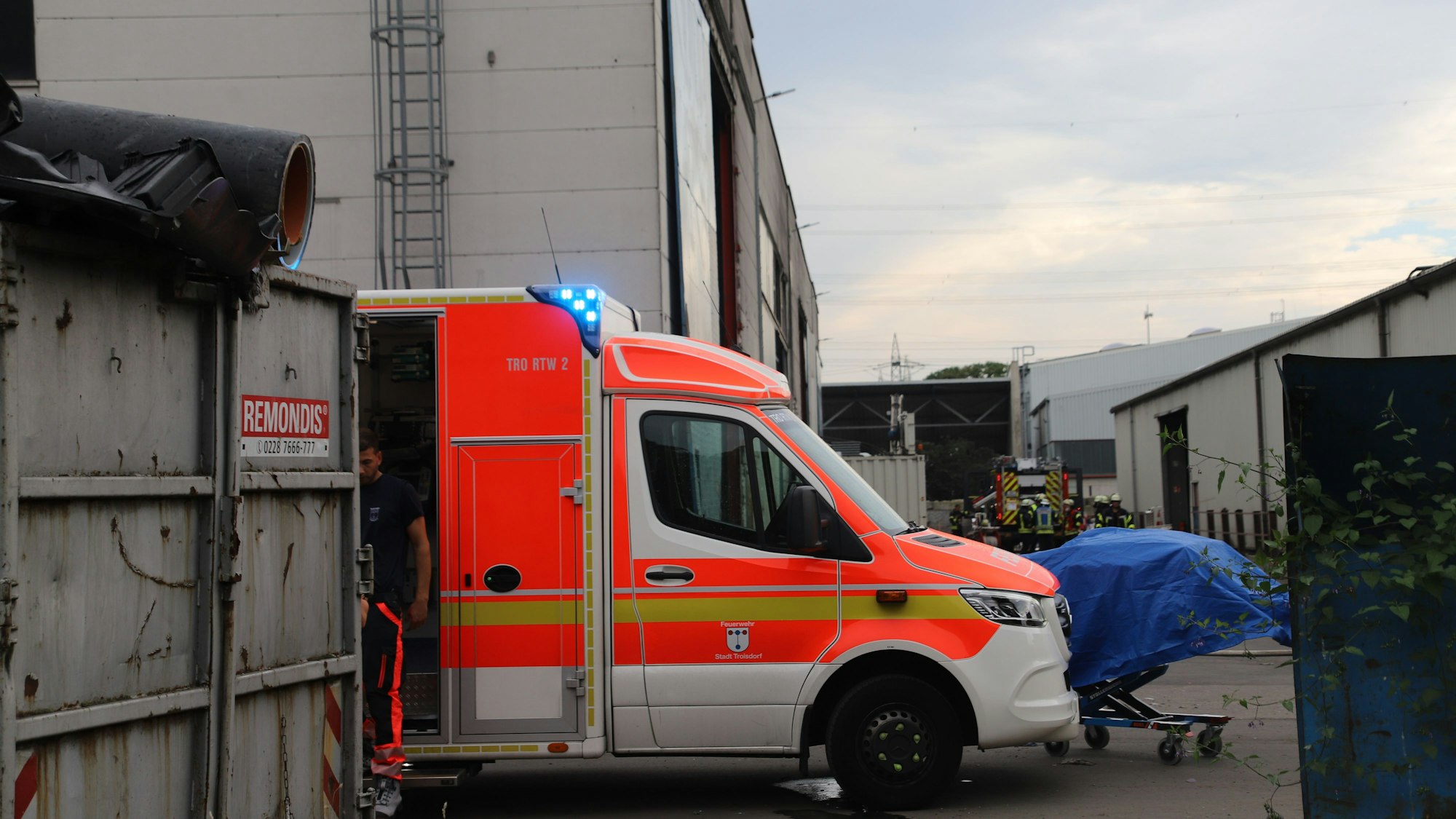 Ein Rettungswagen steht neben einem großen Container.