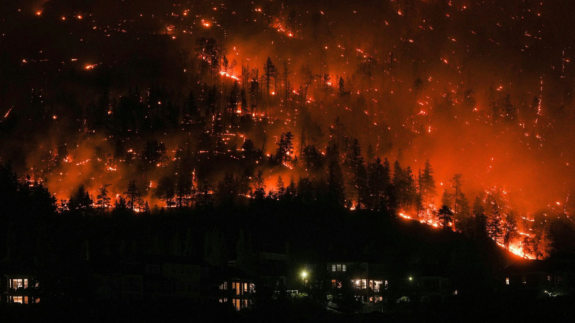dpatopbilder - 18.08.2023, Kanada, West Kelowna: Ein Waldbrand am McDougall Creek an einem Berghang oberhalb von Häusern.
