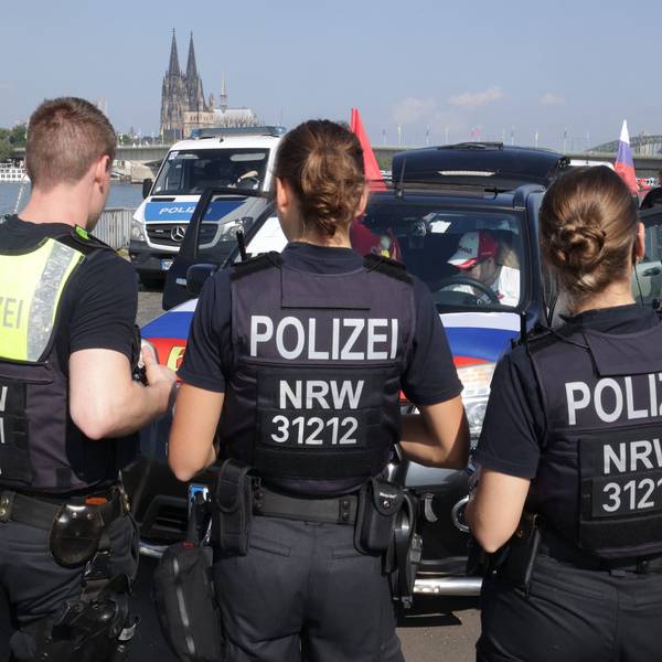 Polizisten stehen vor Autos mit russischen Fahnen.