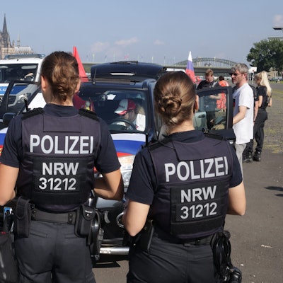 Polizisten stehen vor Autos mit russischen Fahnen.