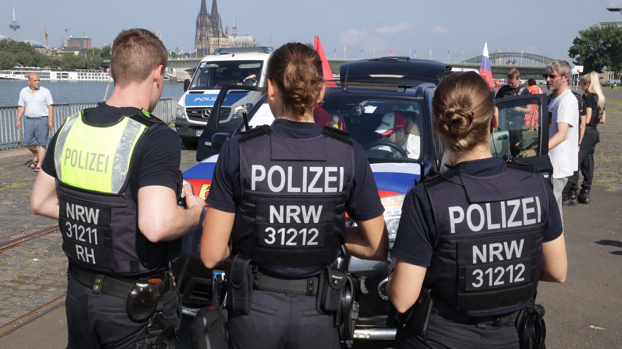 Polizisten stehen vor Autos mit russischen Fahnen.