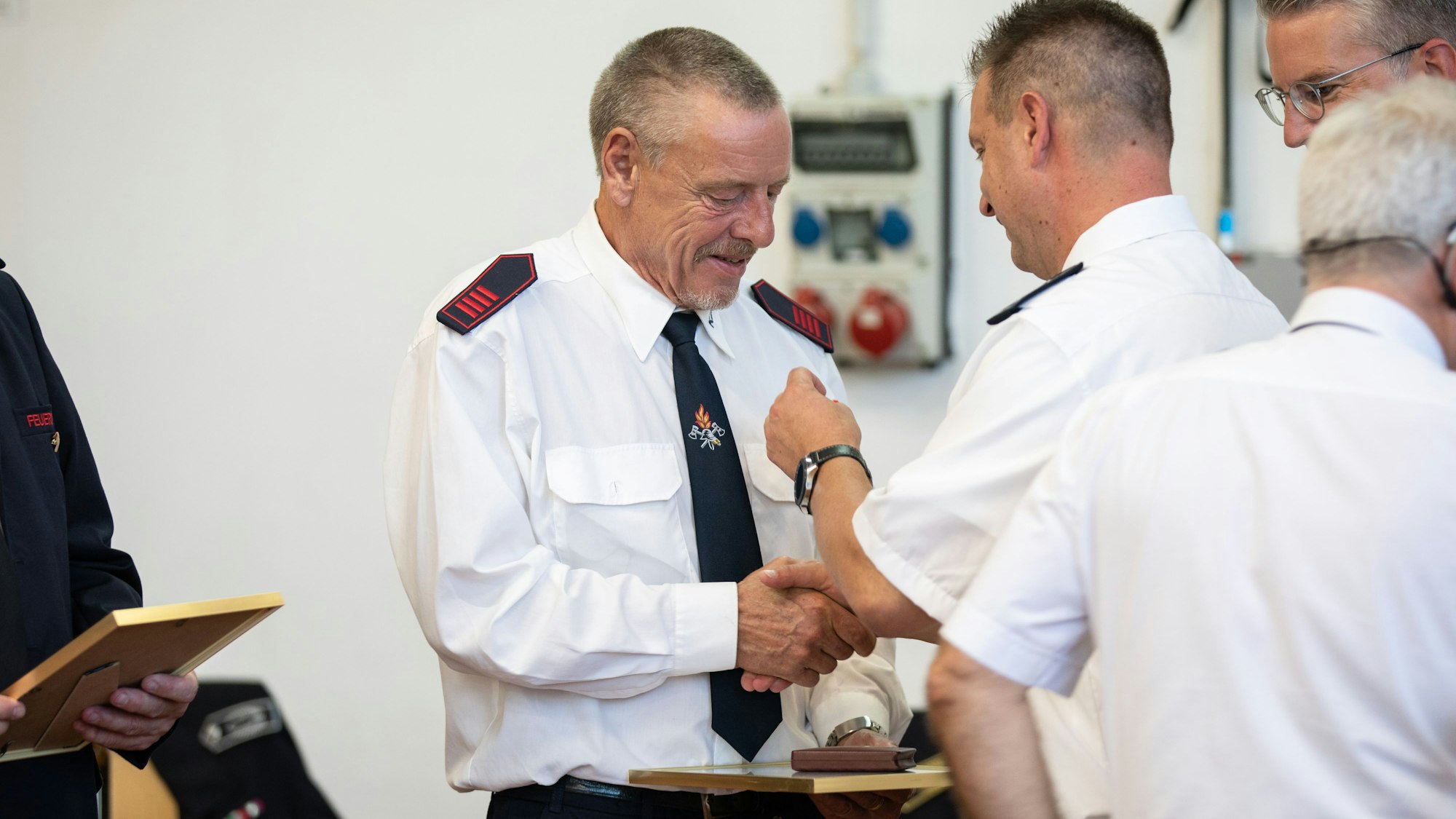 Ein Feuerwehrmann bekommt eine Ehrennadel angesteckt.