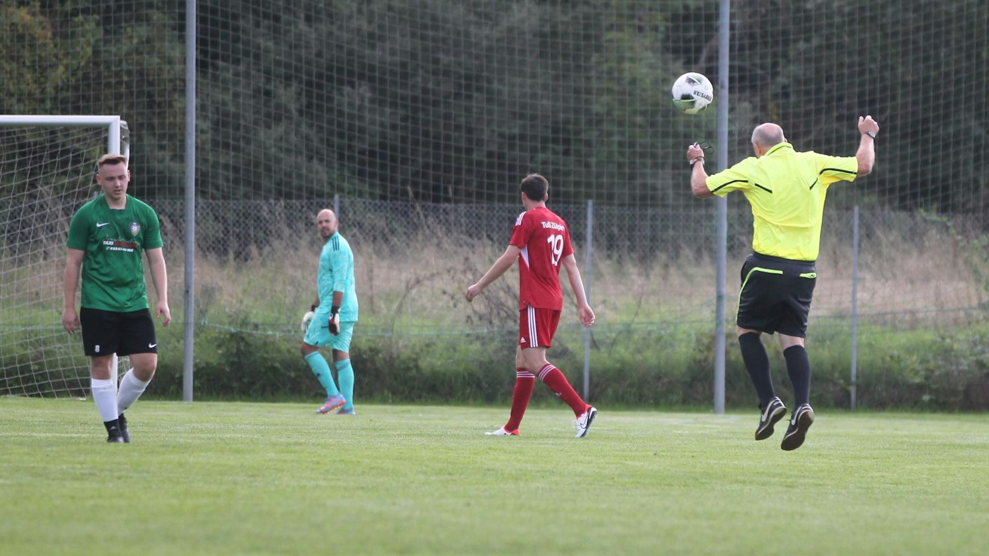 Der Schiedsrichter köpft einen Ball.