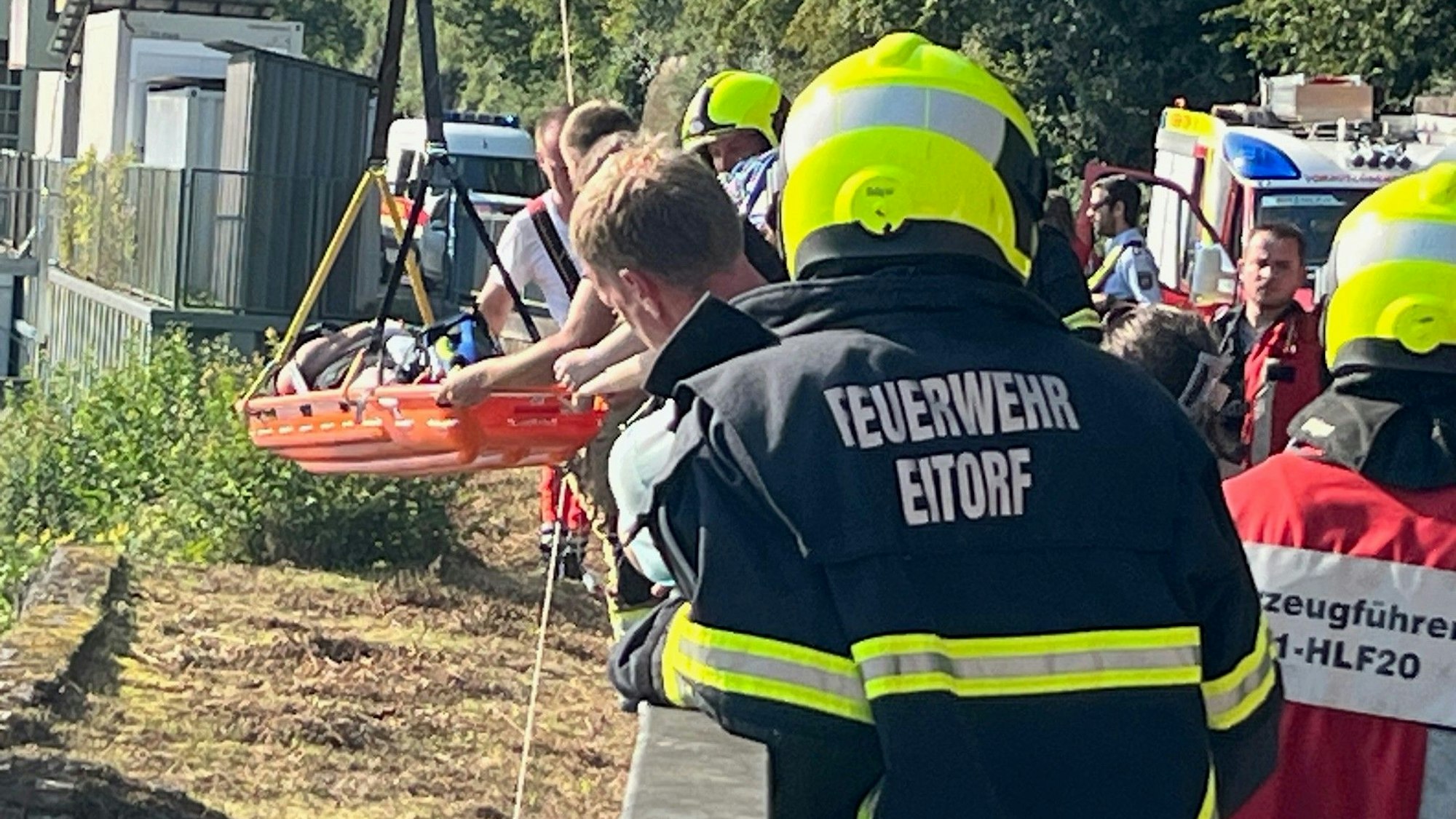 Mit einer Trage heben Feuerwehrleute die völlig erschöpfte 36-Jährige auf die Straße gehoben