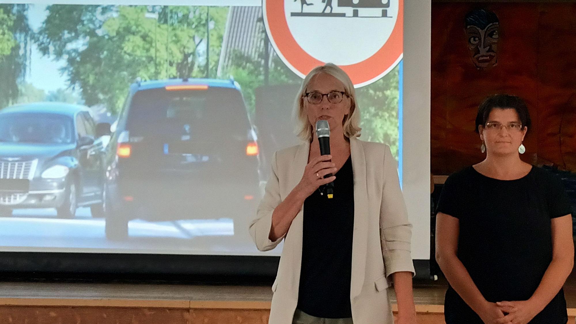 Claudia Wieja (l.) und Schulwegsexpertin Dr. Tabea Kesting sprechen vor einer in der Anliegerversammlung.