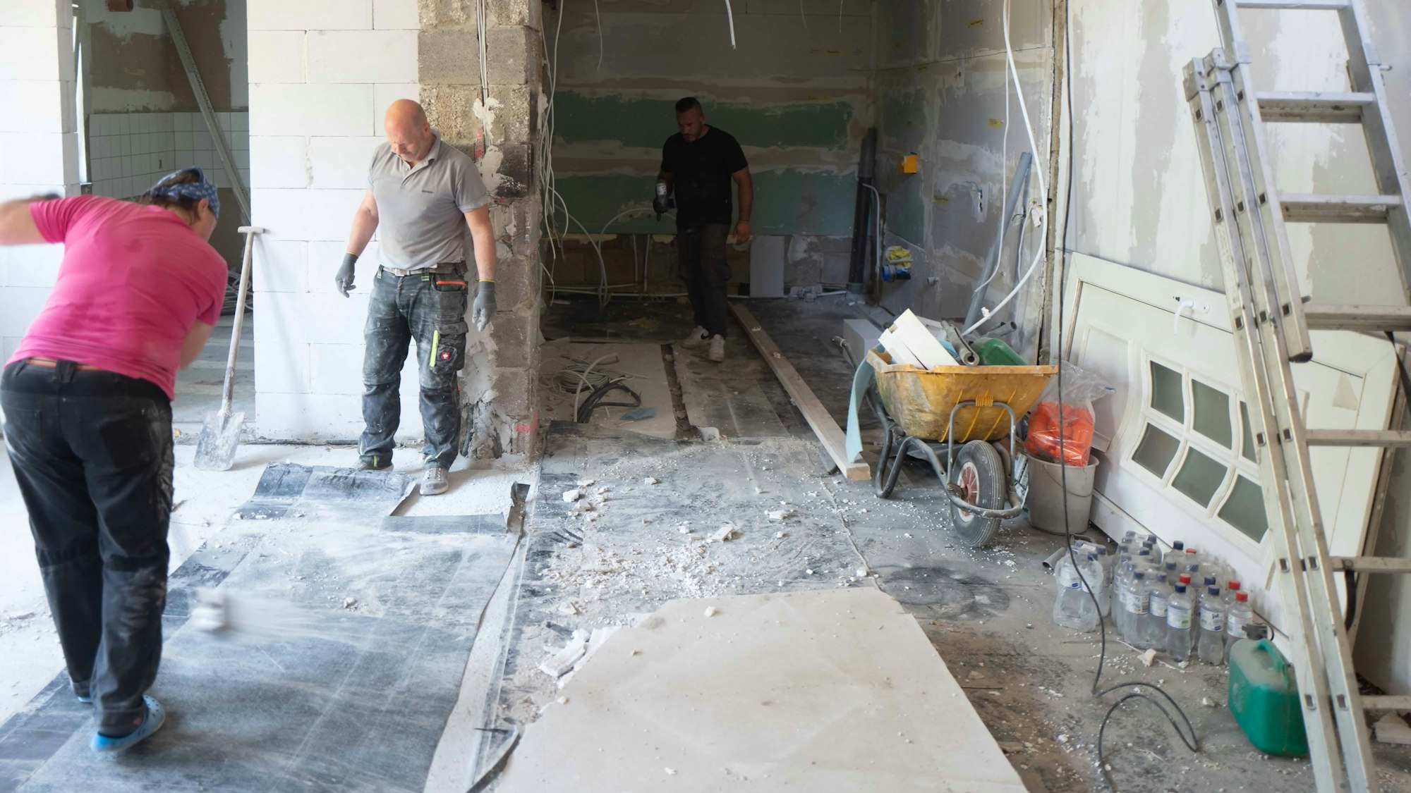 Das Bild zeigt zwei Helfer bei der Arbeit. Sie stehen im Rohbau des Hauses.