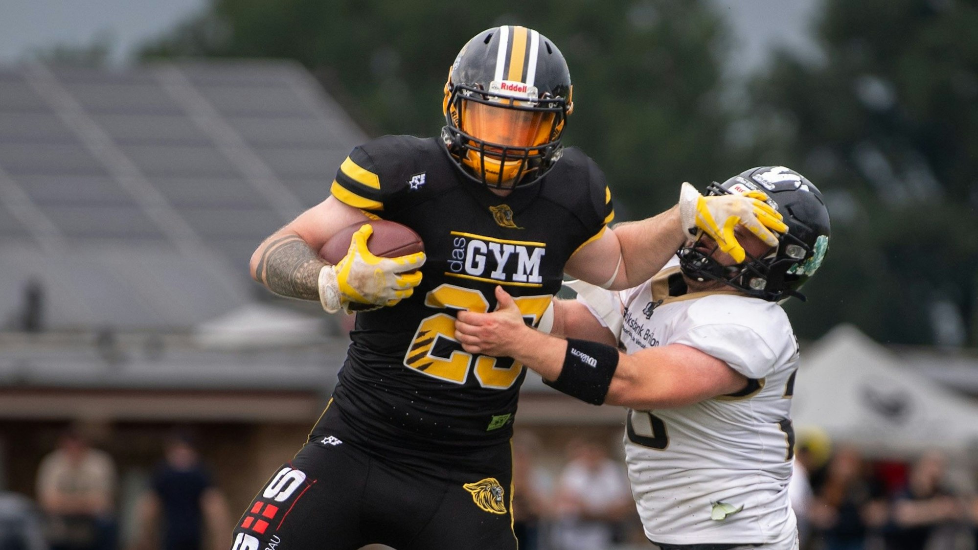Zweikampf zwischen zwei Football-Spielern. Der ballführende Spieler greift dem Gegner ins Gesicht.