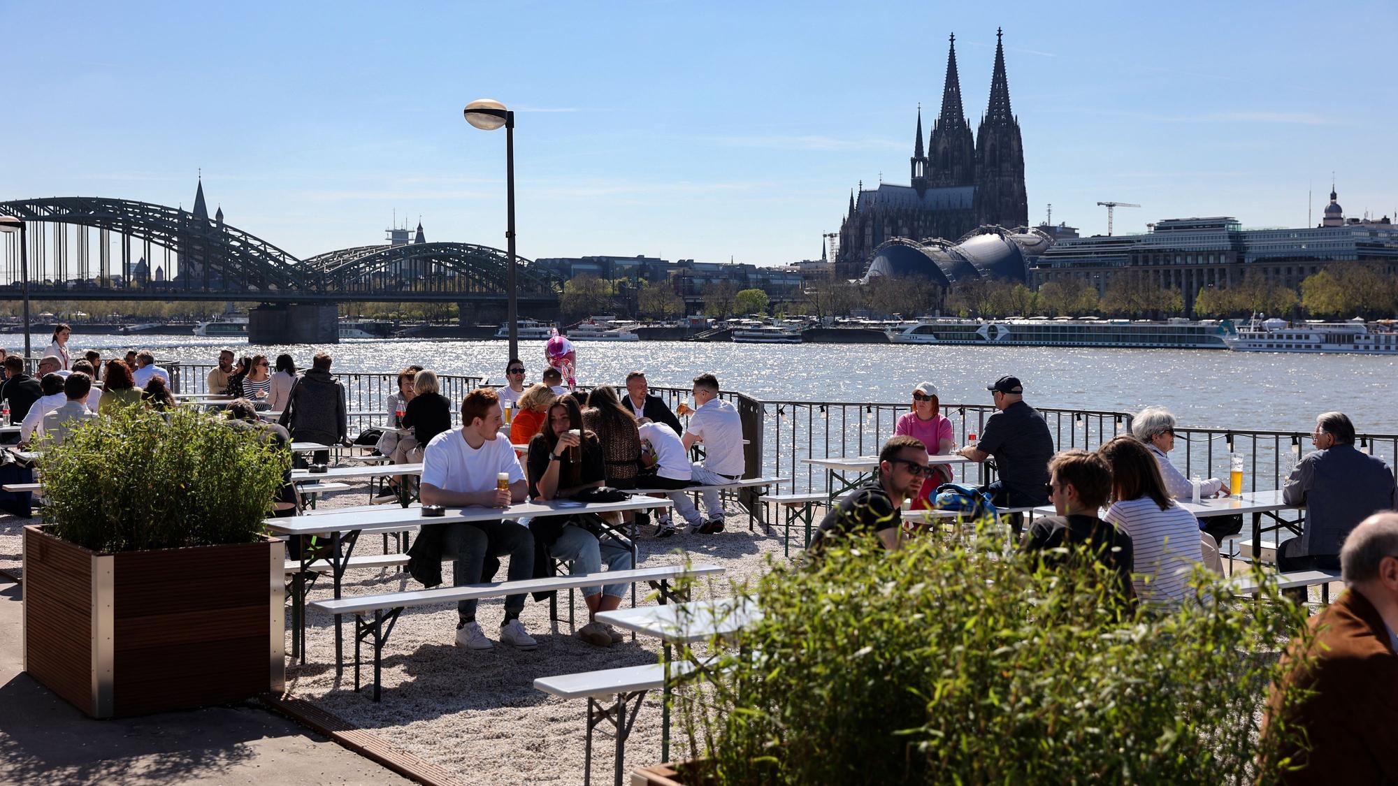 Menschen sitzen an den Rheinterassen in Deutz.