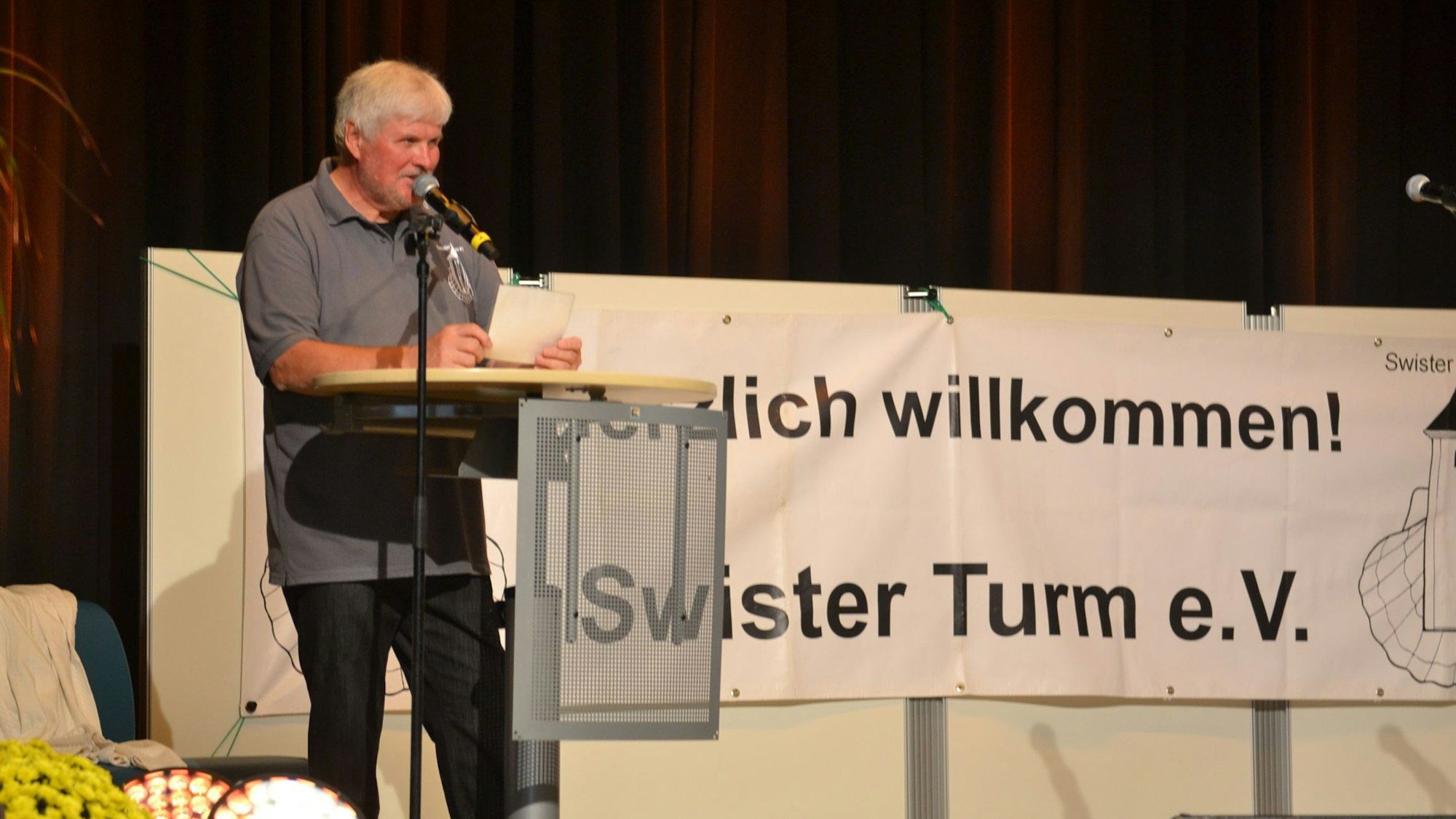 Gerd Burghof, der Vorsitzende des Swister-Turm-Vereins, steht an einem Rednerpult im Forum in Weilerswist.