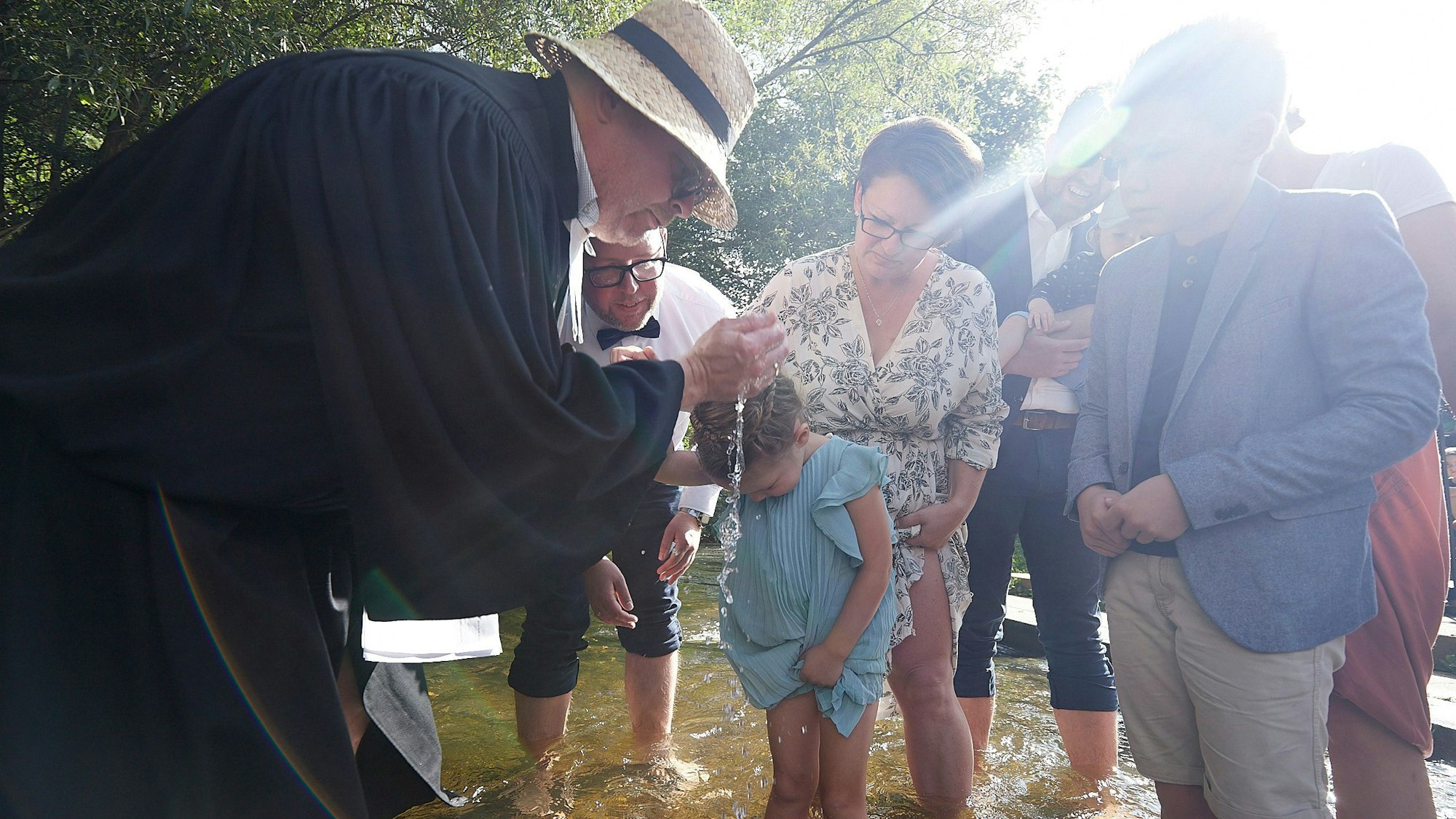 Ein Priester tauft ein kleines Mädchen.