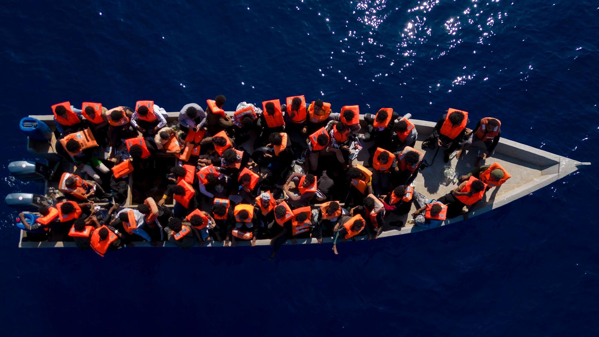 Migranten aus Eritrea, Libyen und dem Sudan sitzen in einem Holzboot, bevor sie von Helfern der spanischen Nichtregierungsorganisation Open Arms im Mittelmeer, etwa 30 Meilen nördlich von Libyen, unterstützt werden. (Archivbild)