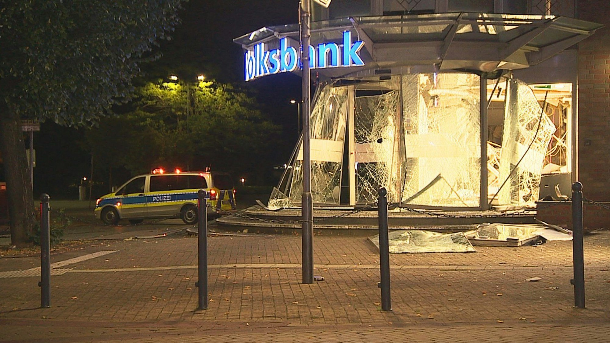 Ein Polizeiauto steht vor einem gesprengten Geldautomaten im Vorraum einer Bank