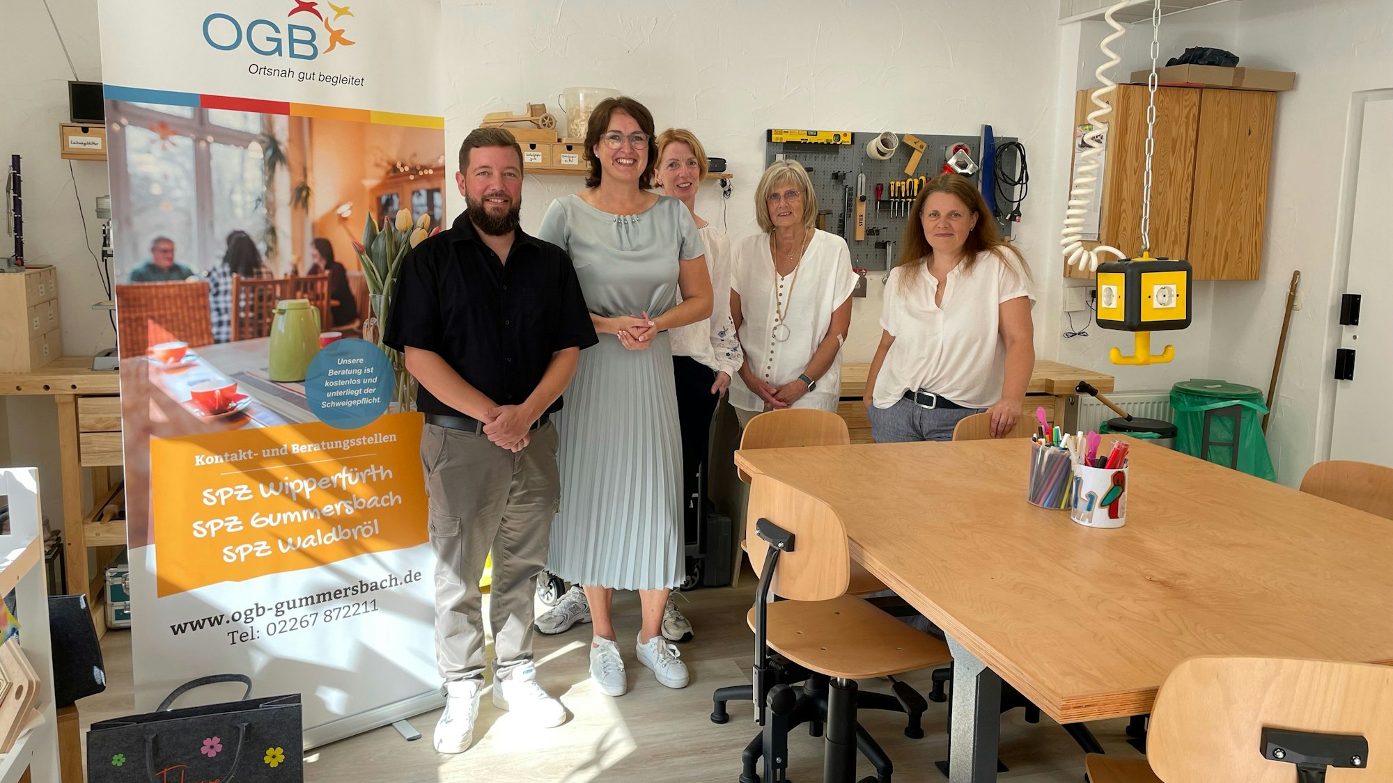 Eine Gruppe von Menschen steht lächelnd hinter einem Basteltisch.