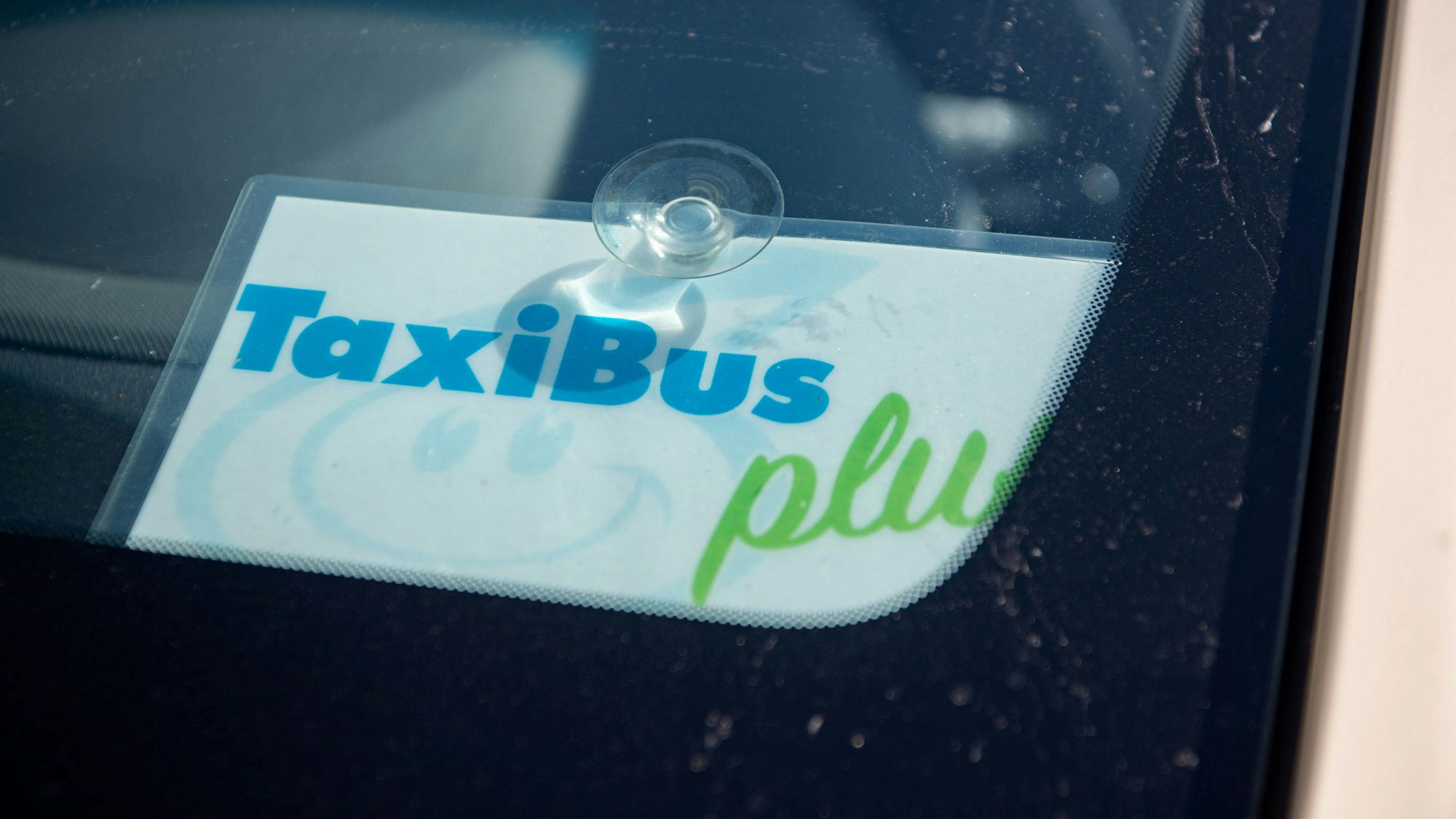 Das Bild zeigt ein Schild in einem Taxi, das kenntlich macht, dass es sich um einen TaxiBus handelt.